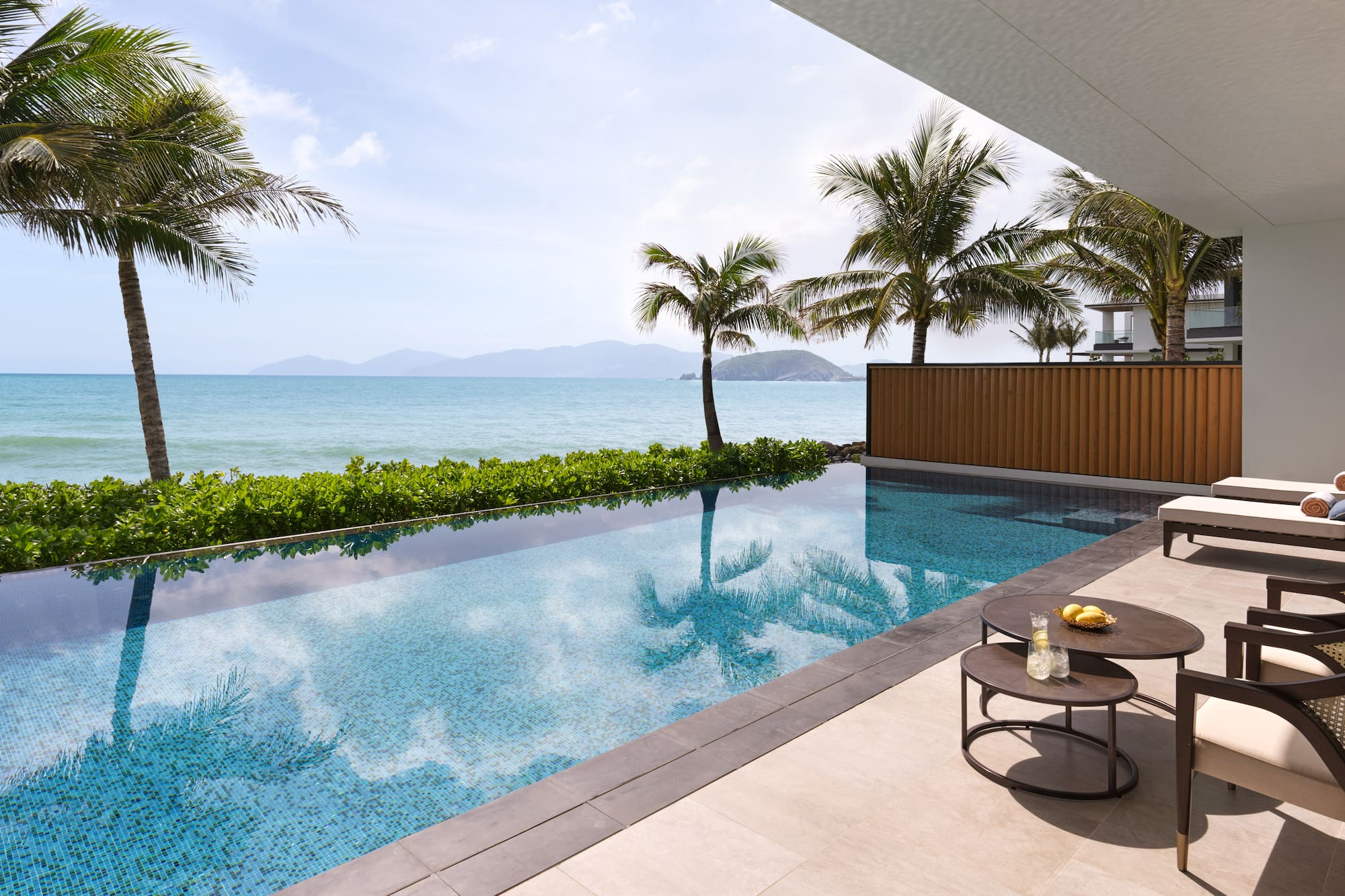 a pool with a table and chairs by a house with a body of water