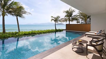 a pool with a table and chairs by a house with a body of water