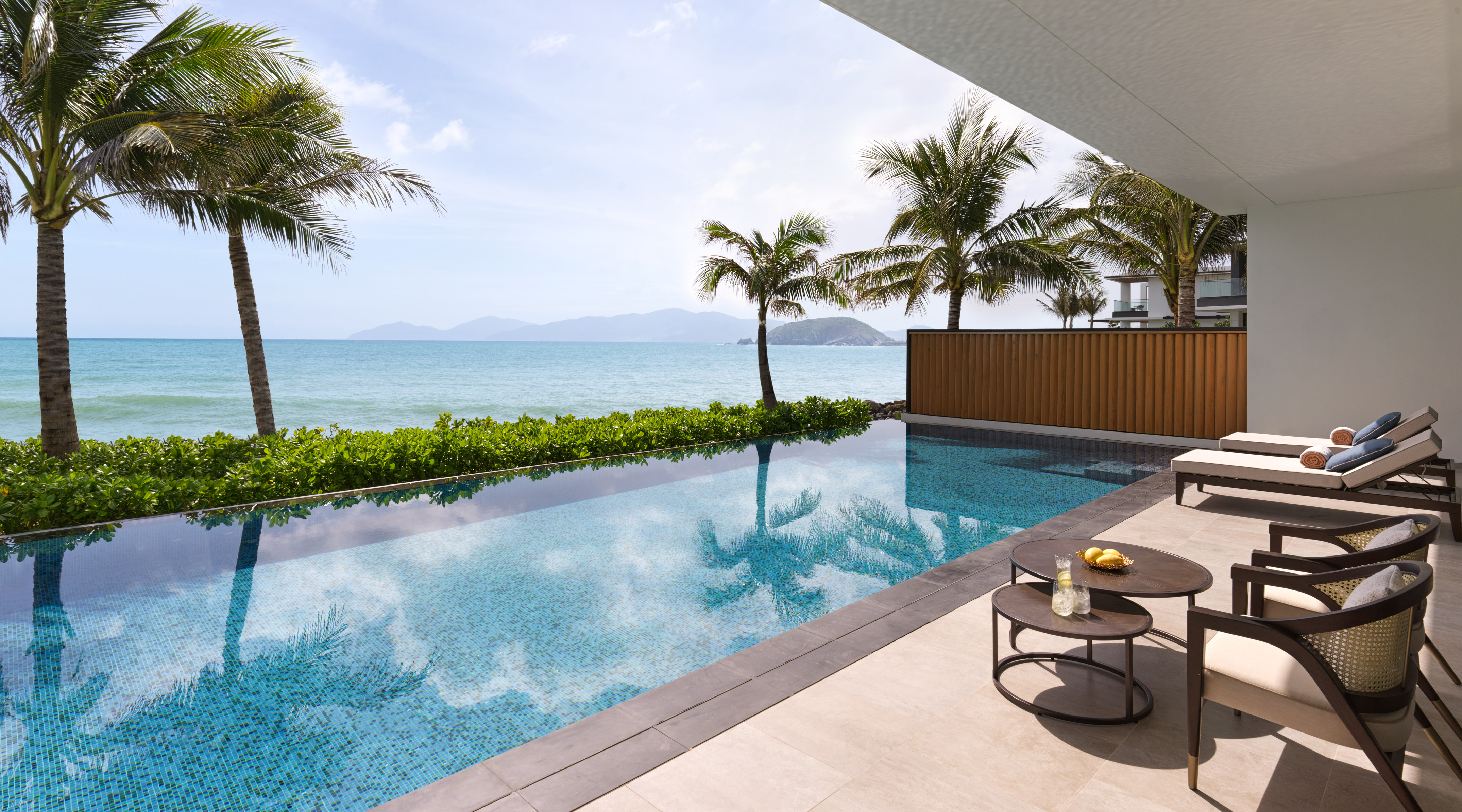 Tropical ocean view infinity pool, luxury resort with palm trees and terrace.