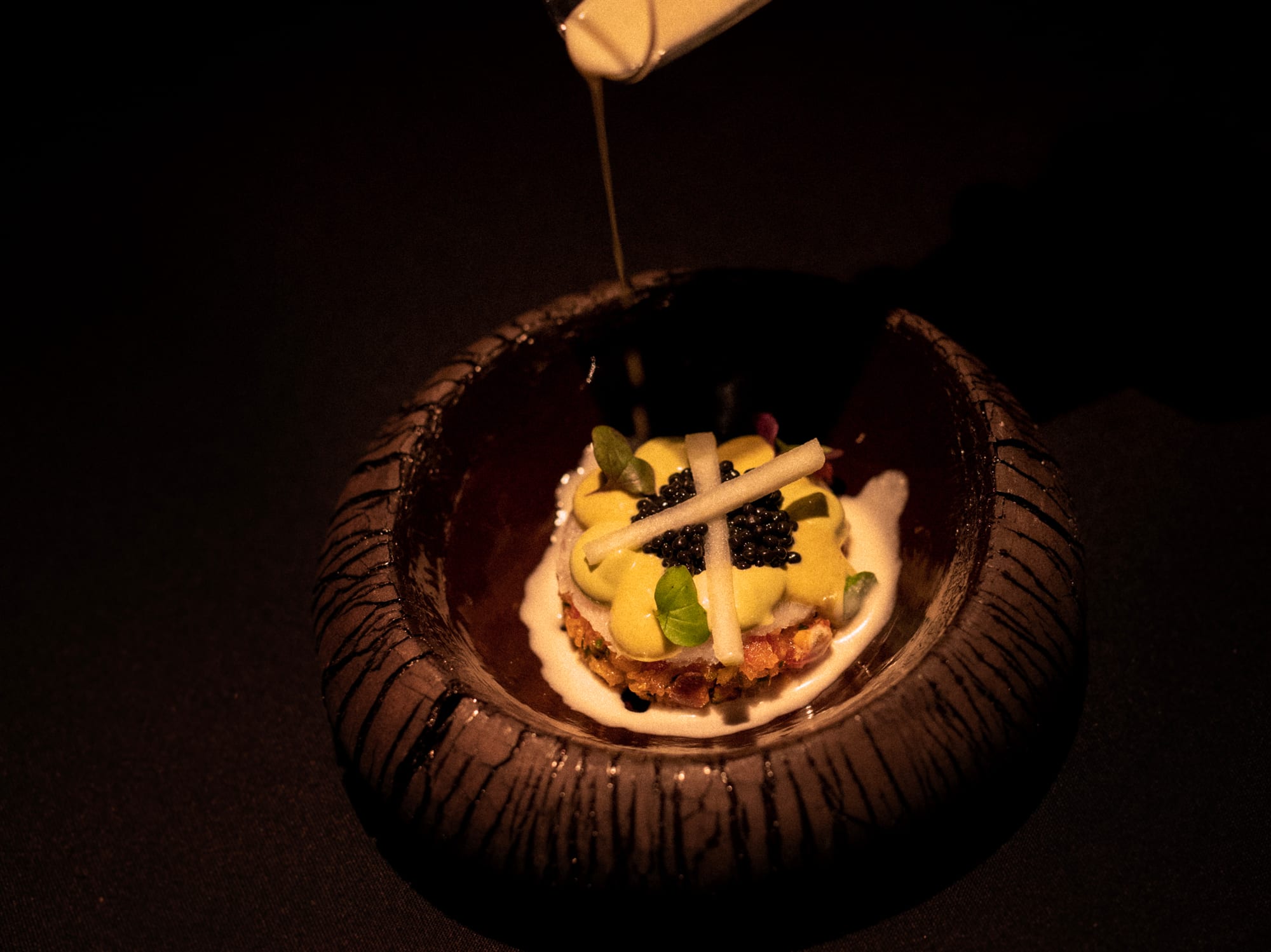 a bowl of food with a white liquid being poured into it