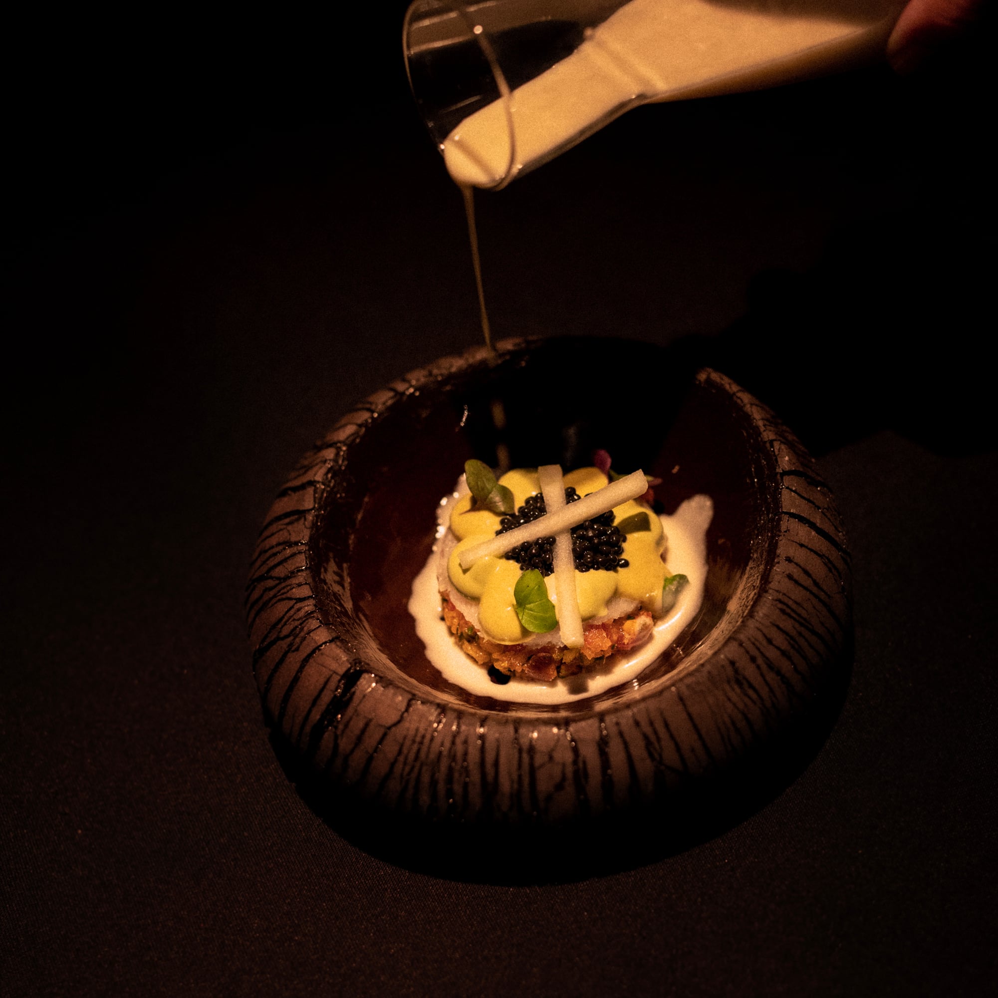 a bowl of food with a white liquid being poured into it