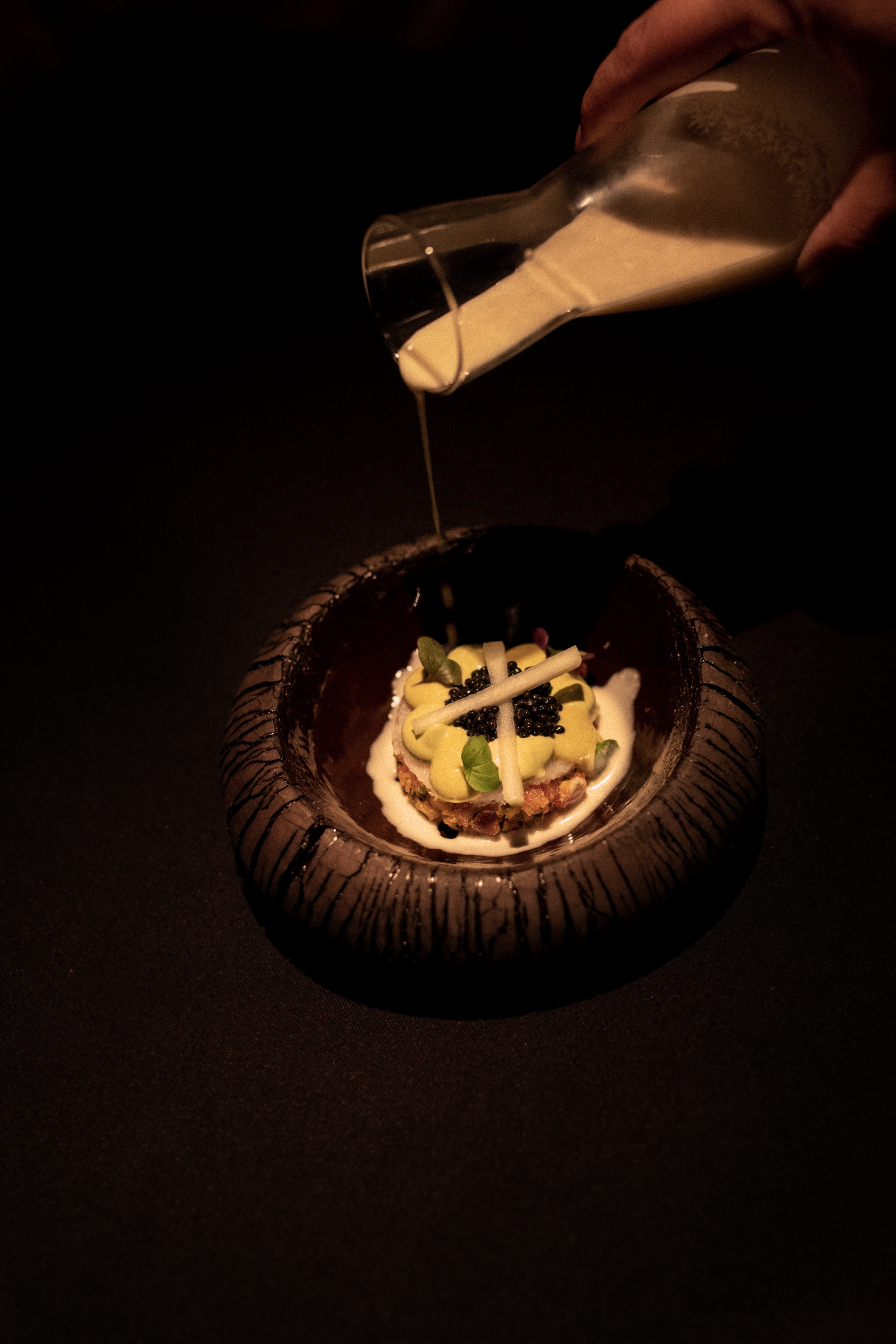 a bowl of food with a white liquid being poured into it