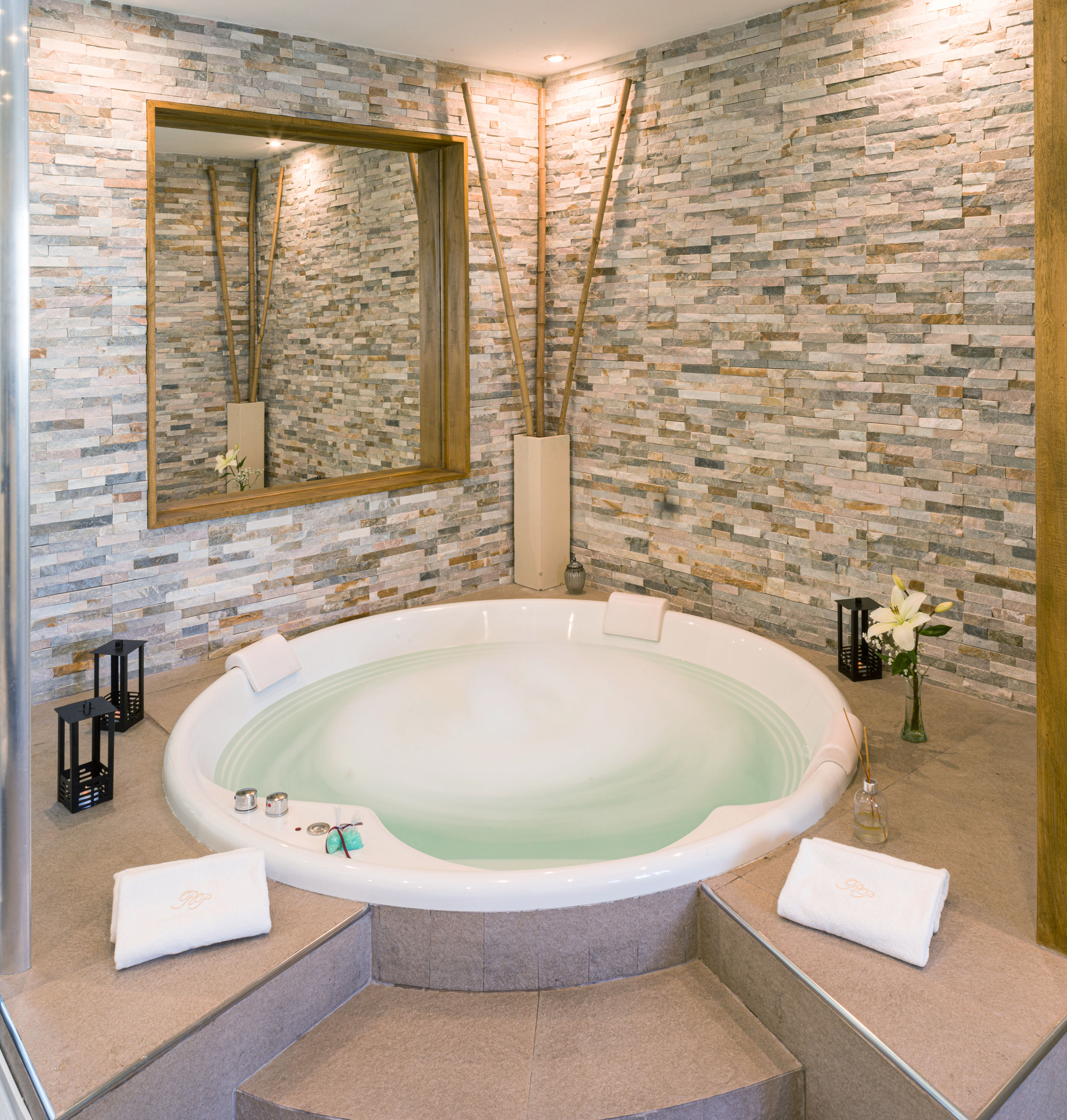 a large round tub in a room with a stone wall