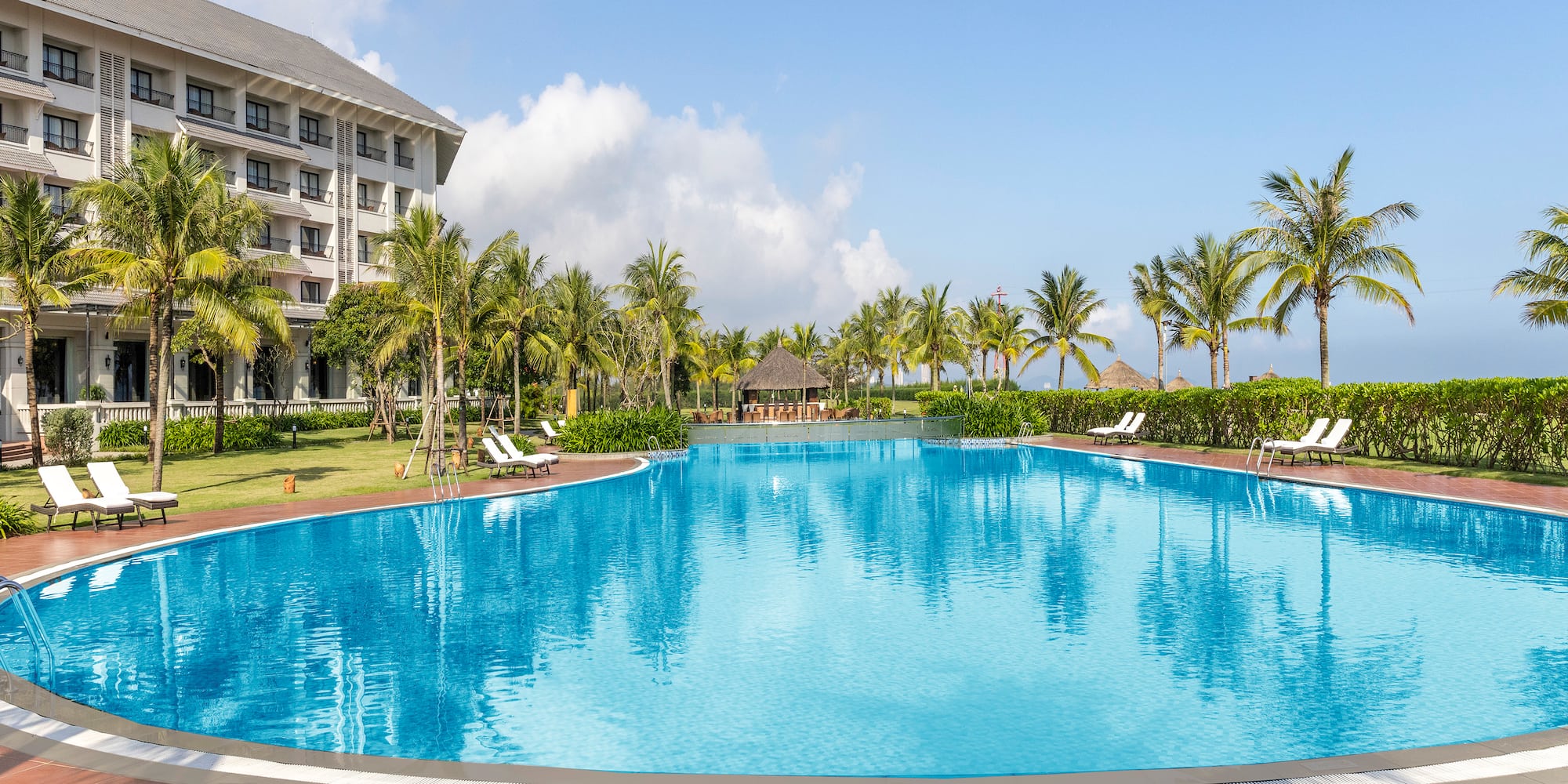 a pool with palm trees and a building in the background