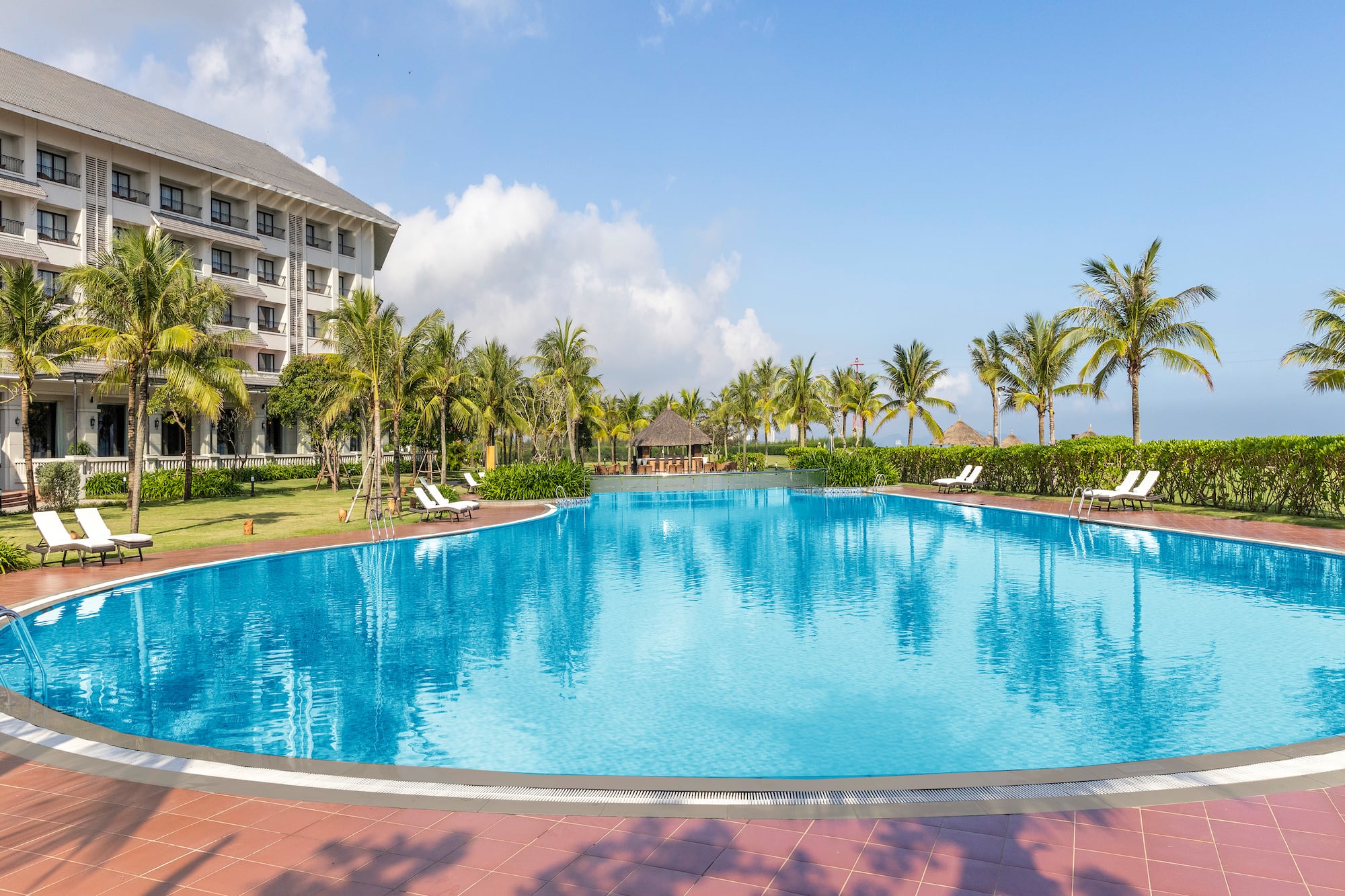 a pool with palm trees and a building in the background