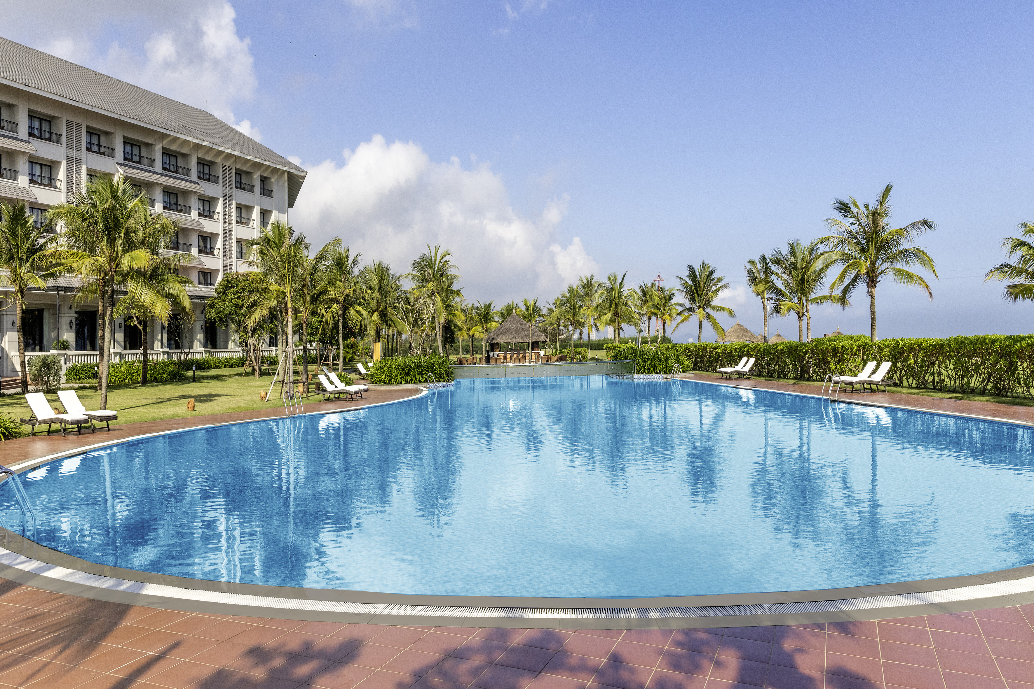 a pool with palm trees and a building in the background