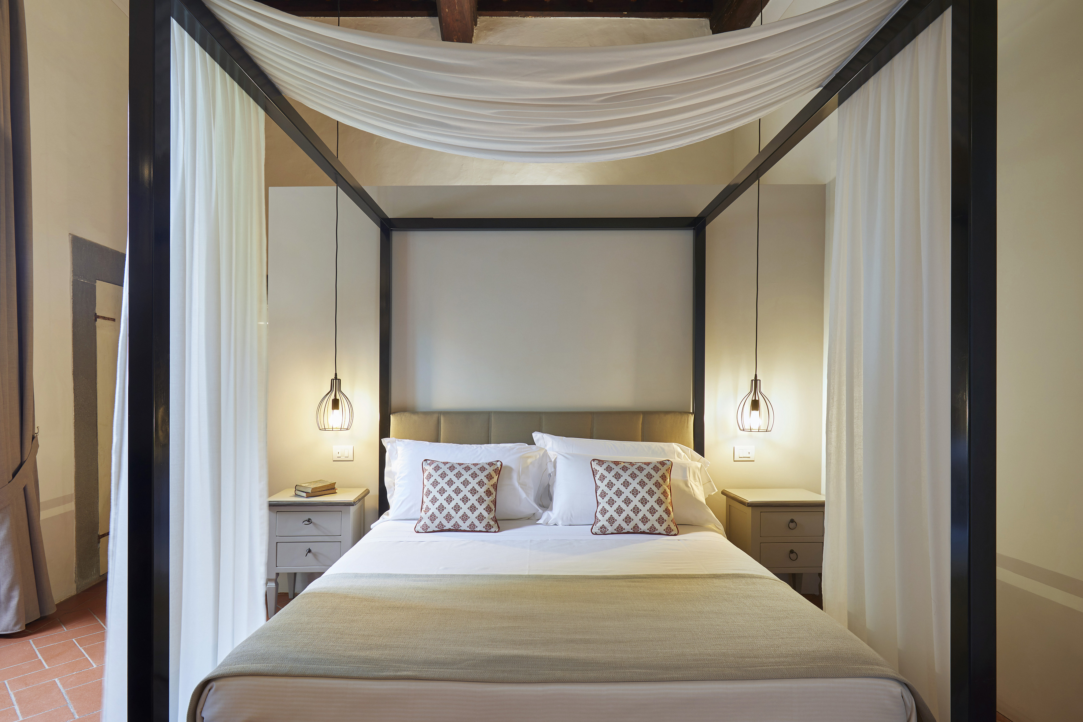 Elegant four-poster canopy bed in a rustic hotel bedroom.