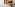 Luxury hotel room with bed, wooden TV console, and lounge area.