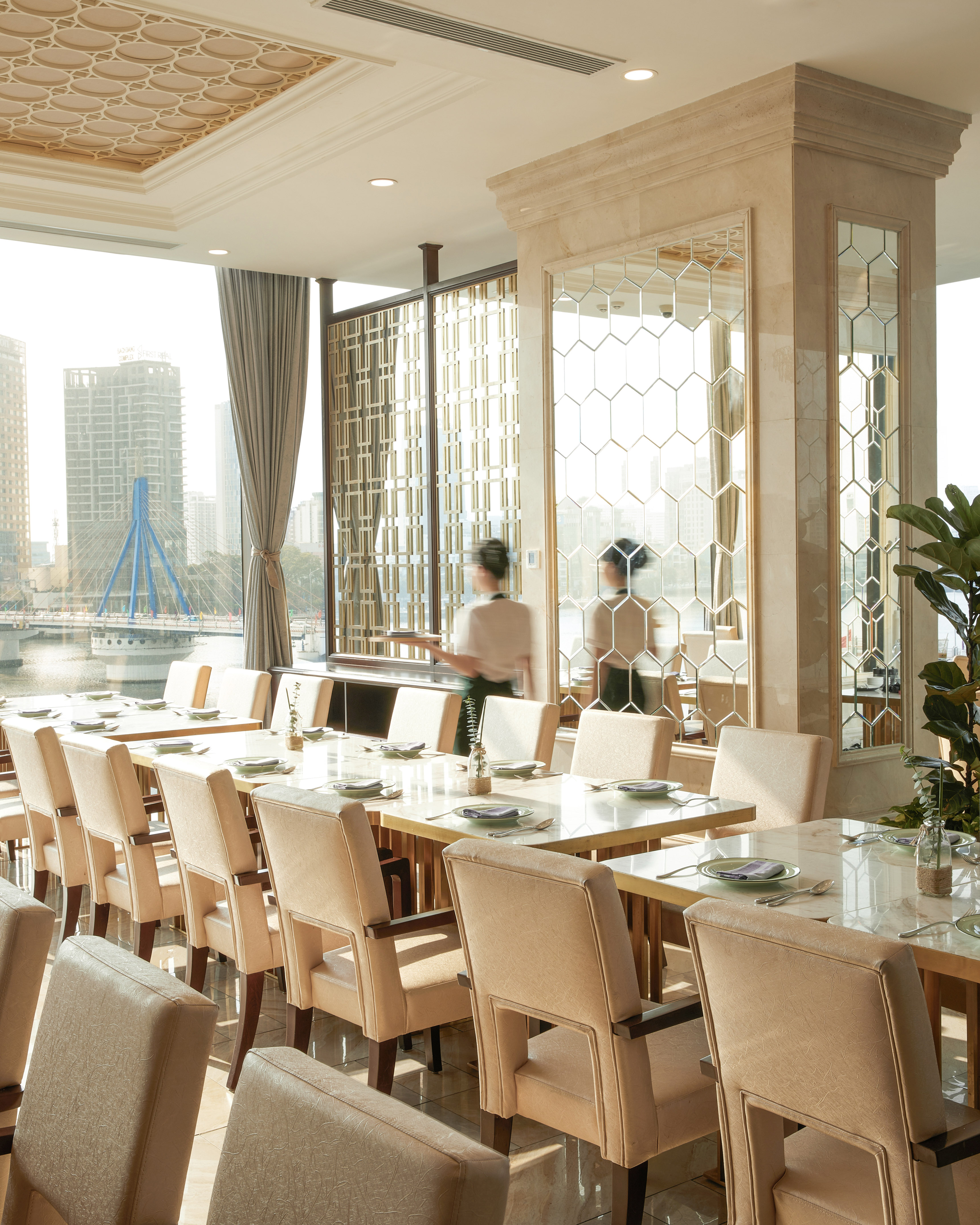 Modern upscale restaurant dining room with city waterfront view and server.