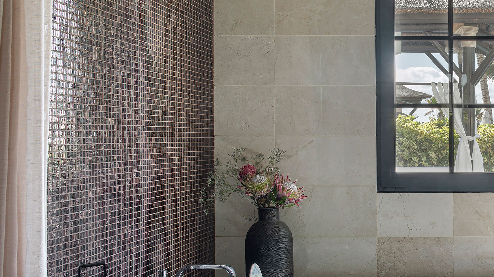 a bathroom with a tub and a vase of flowers