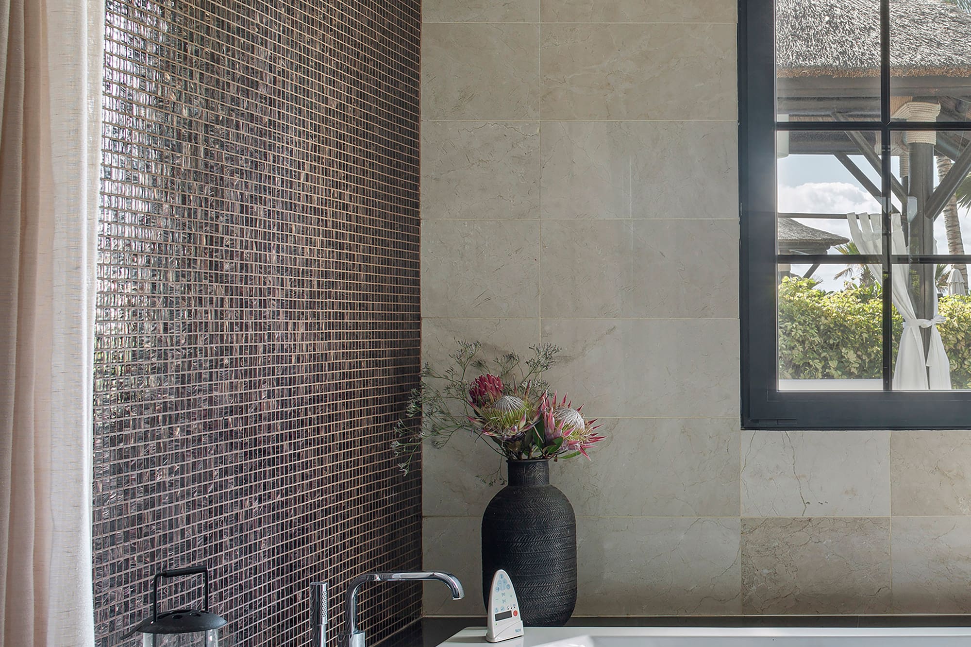 a bathroom with a tub and a vase of flowers
