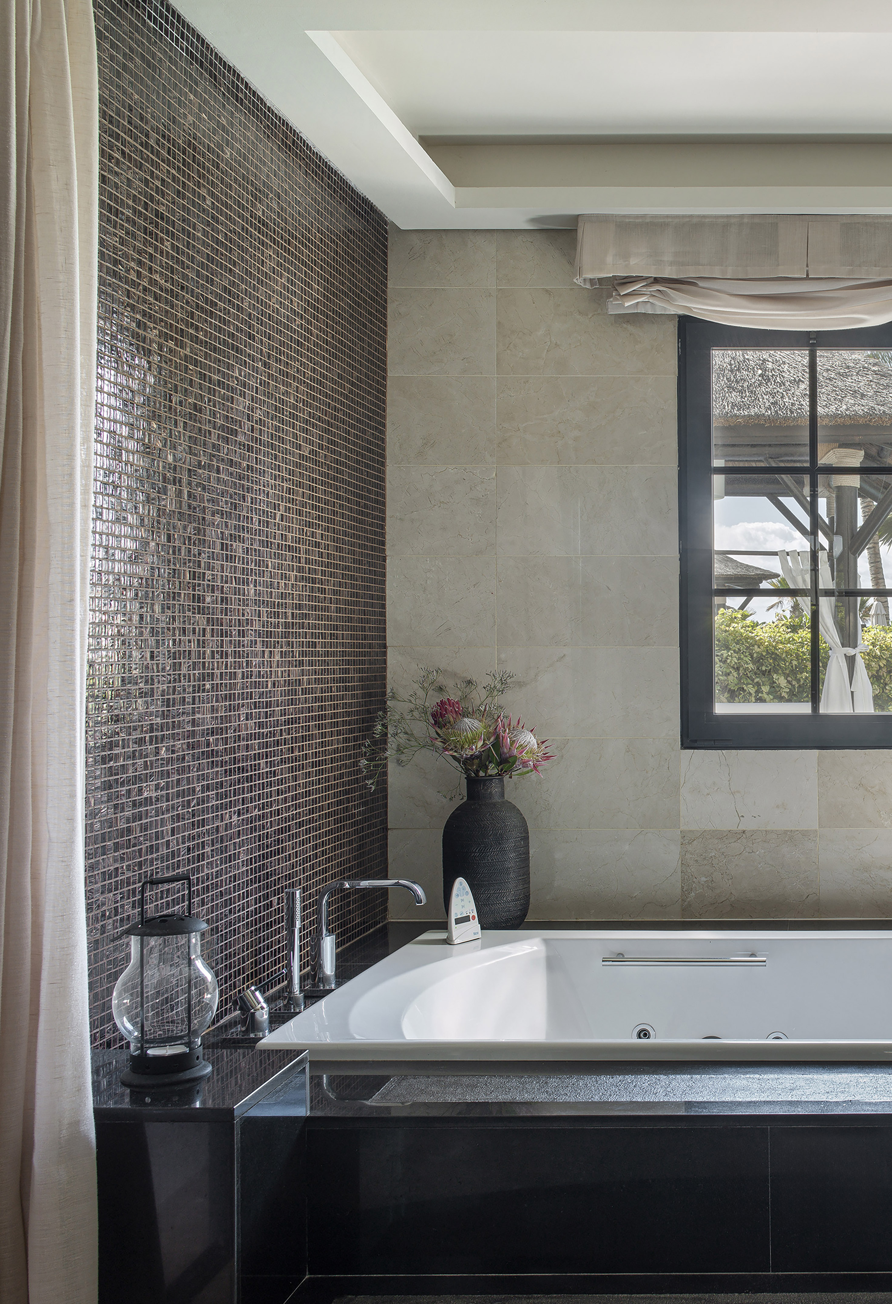 a bathroom with a tub and a vase of flowers