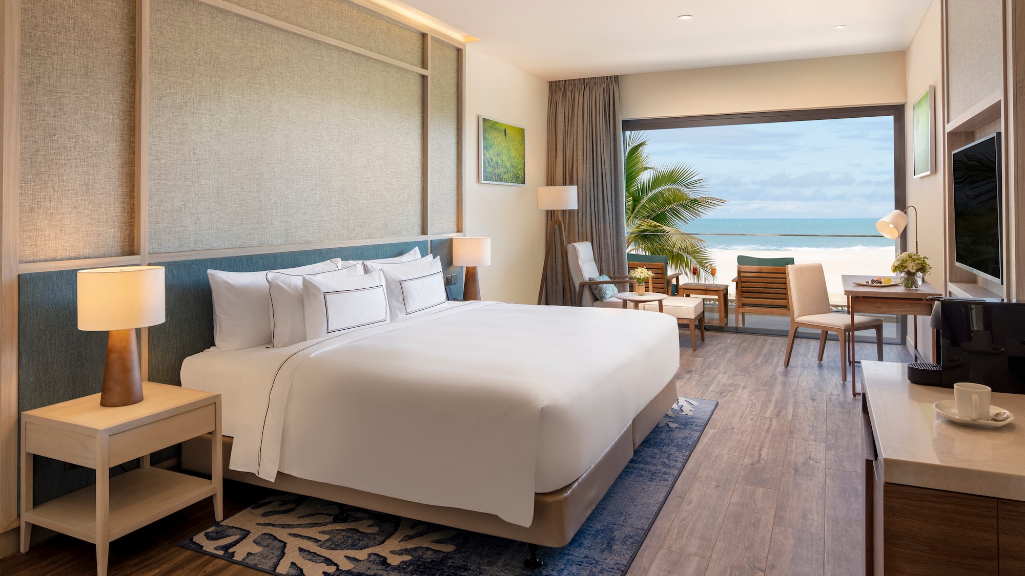 Modern beachfront hotel room with ocean view, large bed, and balcony.