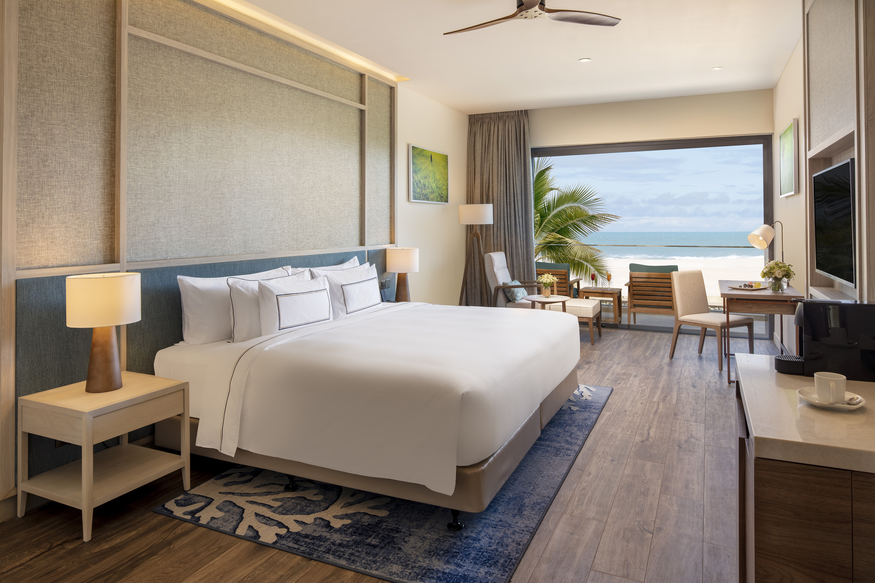 Modern beachfront hotel room with ocean view, large bed, and balcony.