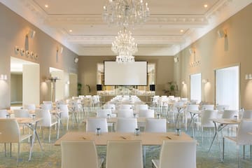 a room with tables and chairs and chandeliers