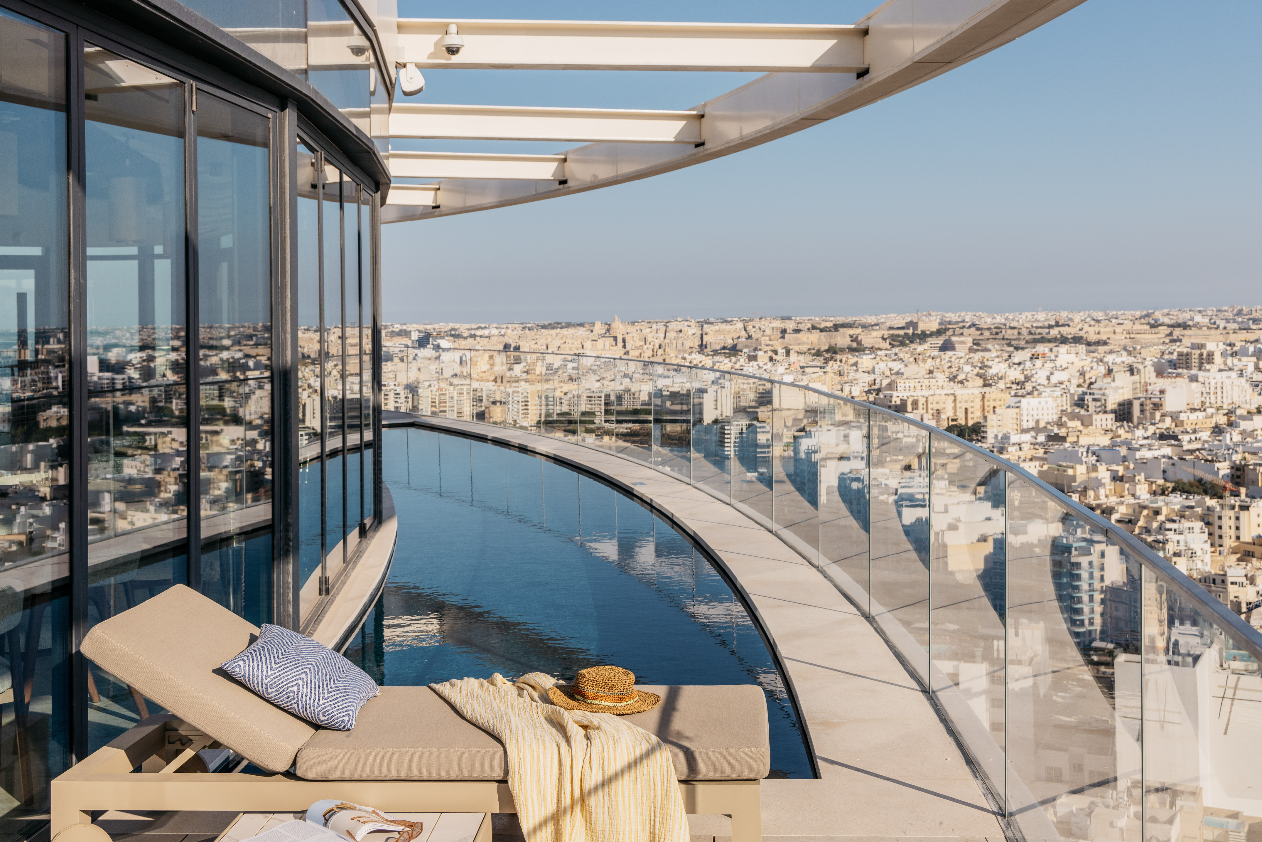 Luxury rooftop infinity pool with sun loungers and expansive city views.