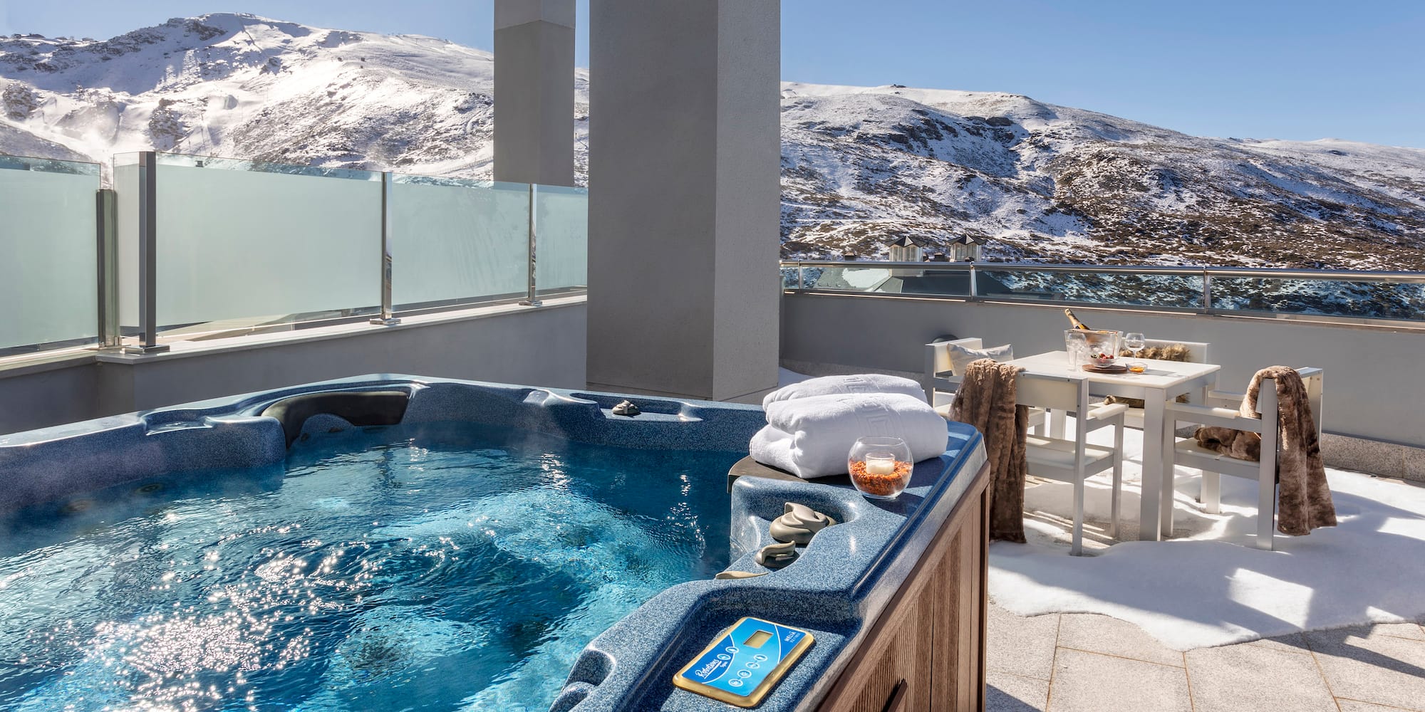 a hot tub on a rooftop with snow covered mountains in the background