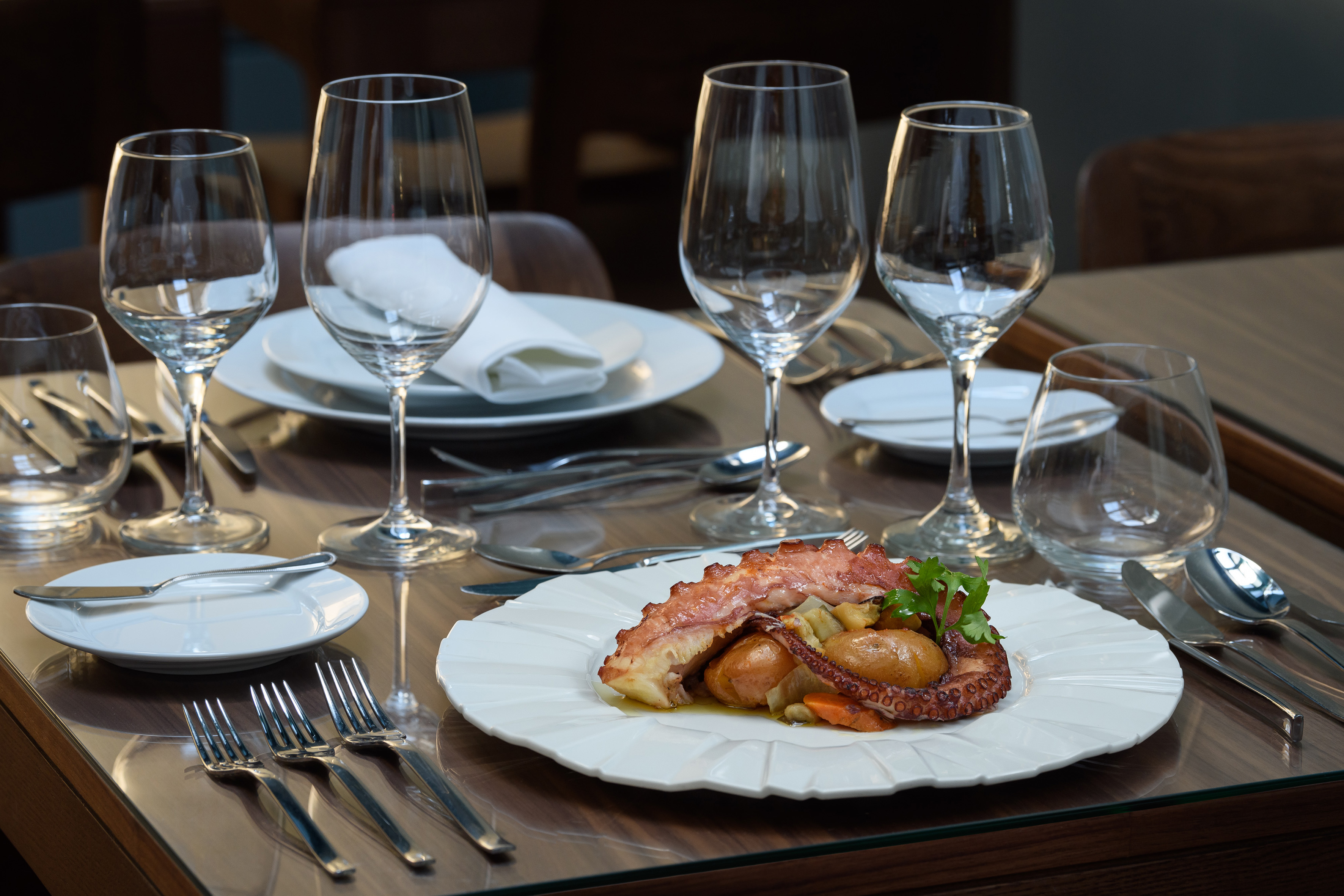 Gourmet octopus dish with baby potatoes on an elegant restaurant table.