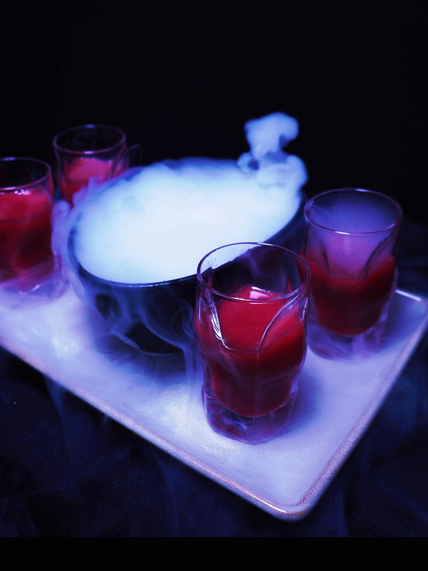 a tray of glasses with liquid and smoke