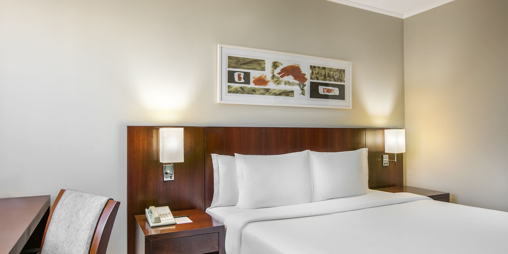 a bed with white sheets and a wood headboard