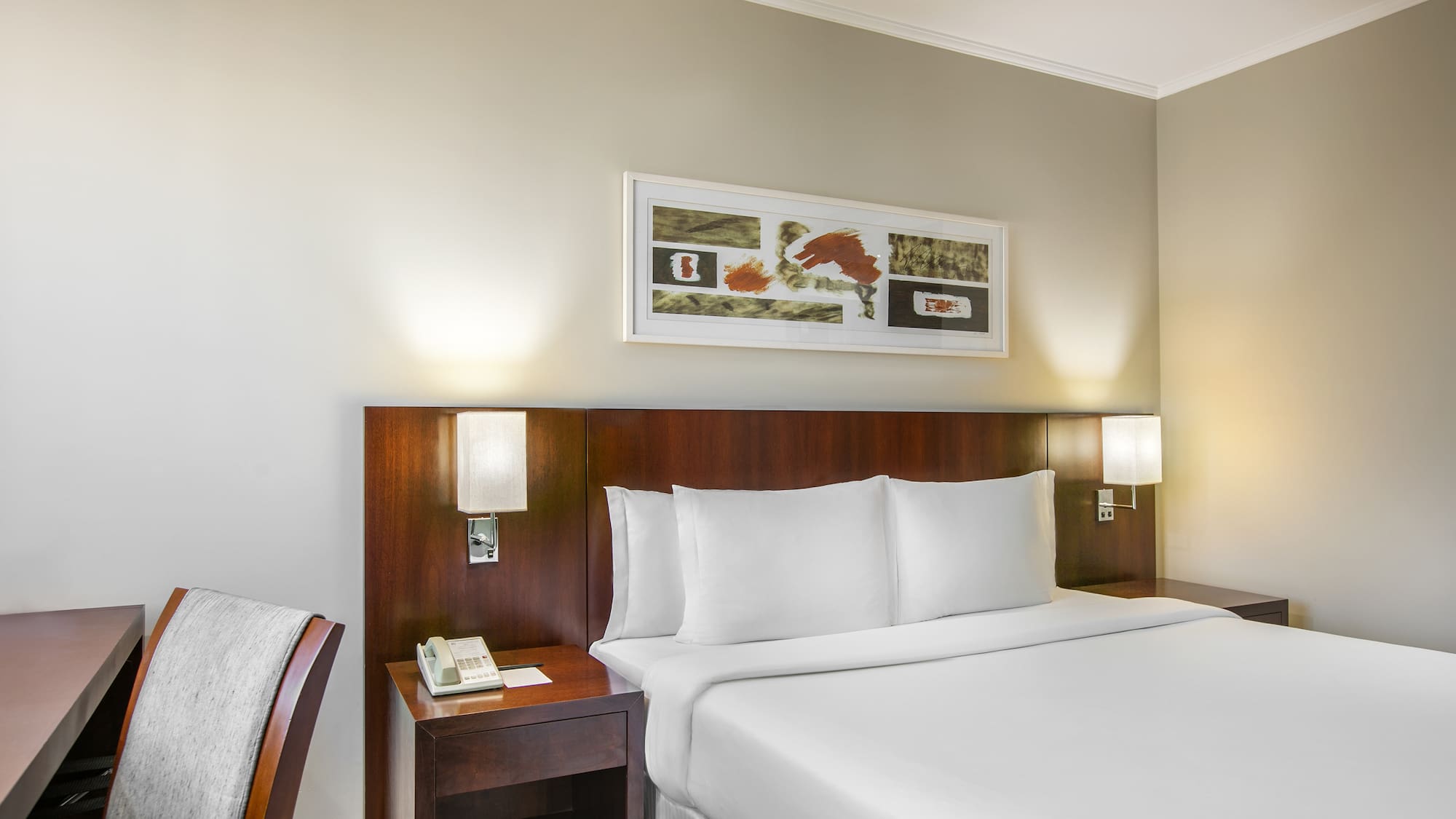 a bed with white sheets and a wood headboard