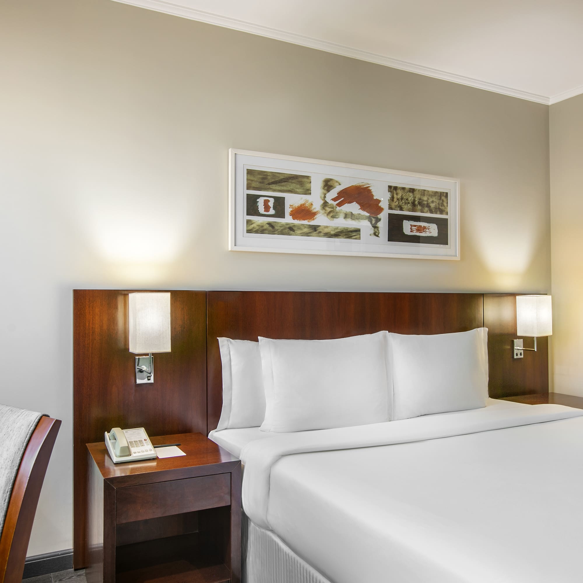 a bed with white sheets and a wood headboard