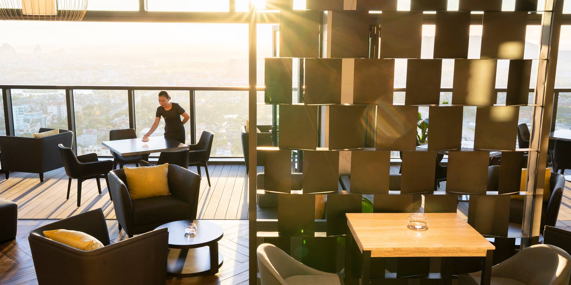 a woman standing in a room with a window and chairs