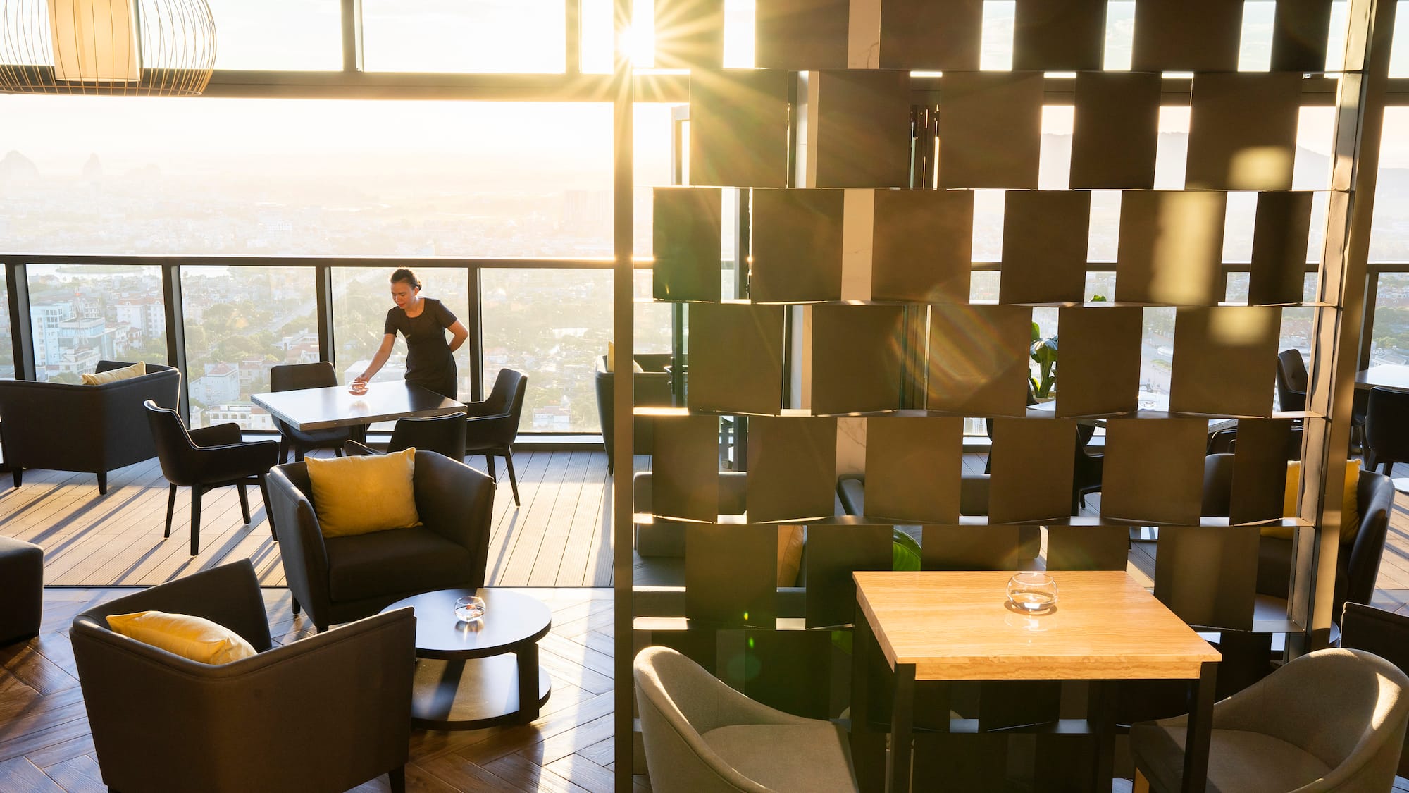 a woman standing in a room with a window and chairs