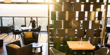 a woman standing in a room with a window and chairs