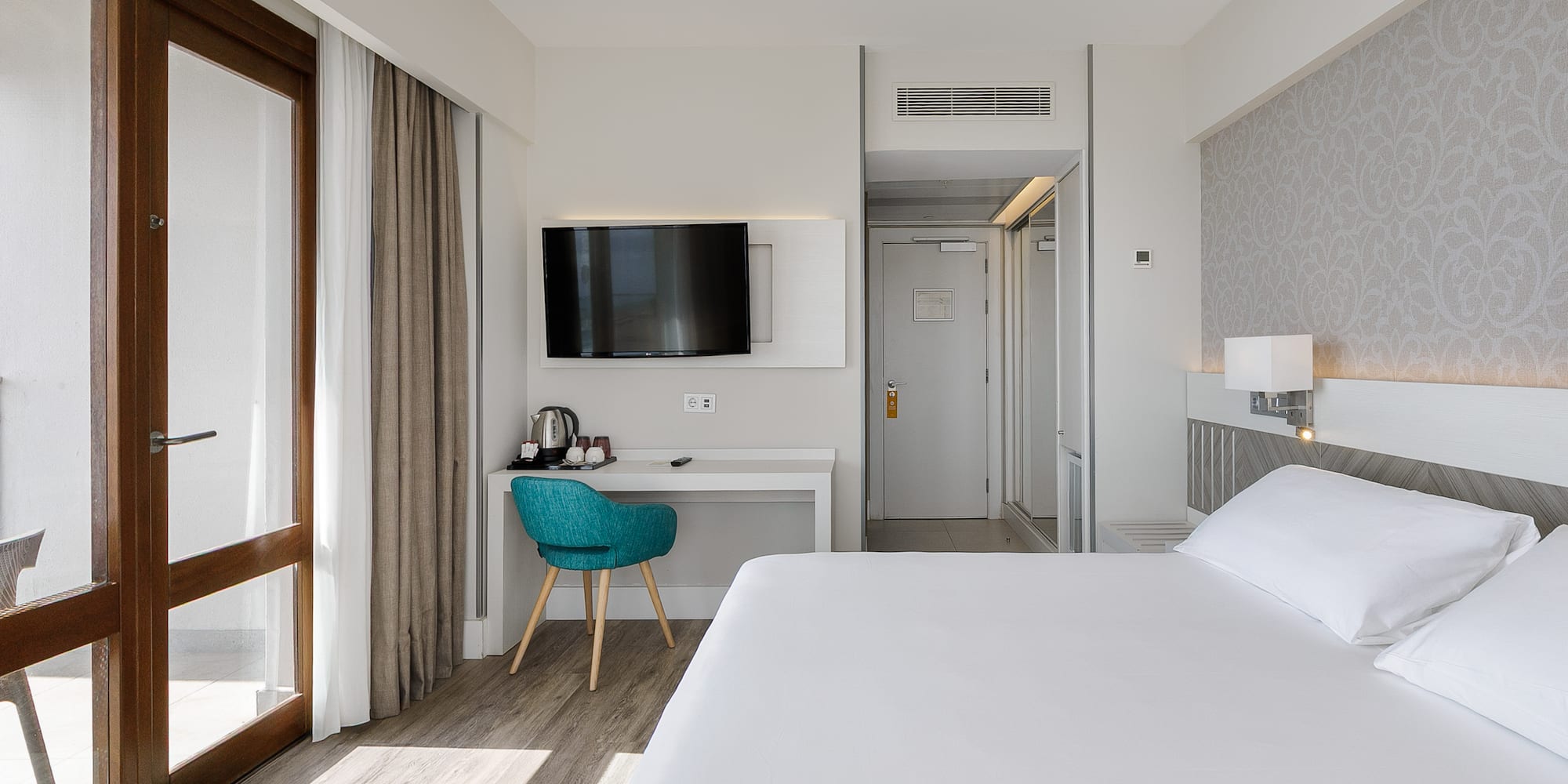 a room with a bed and a desk and a television