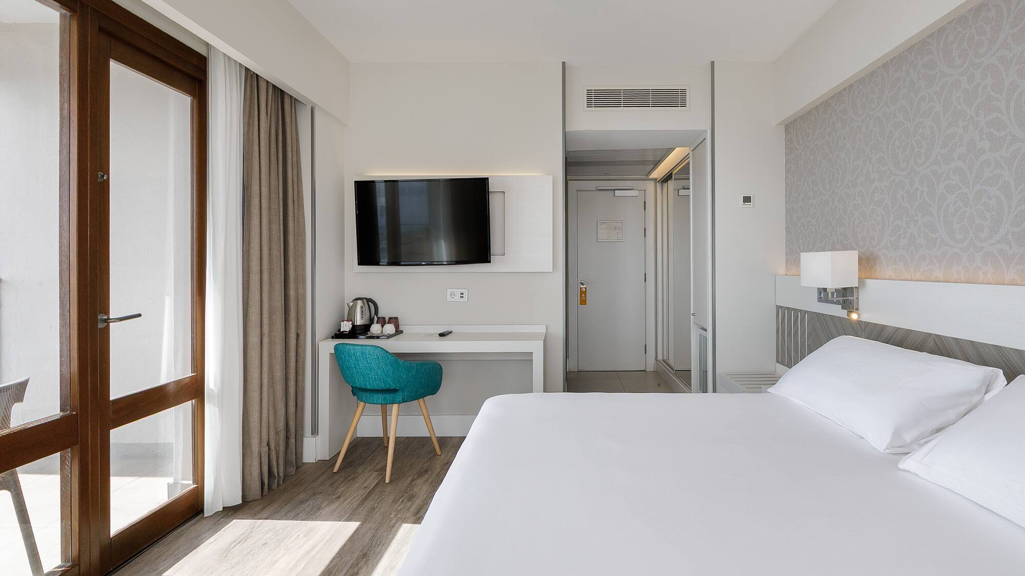 a room with a bed and a desk and a television