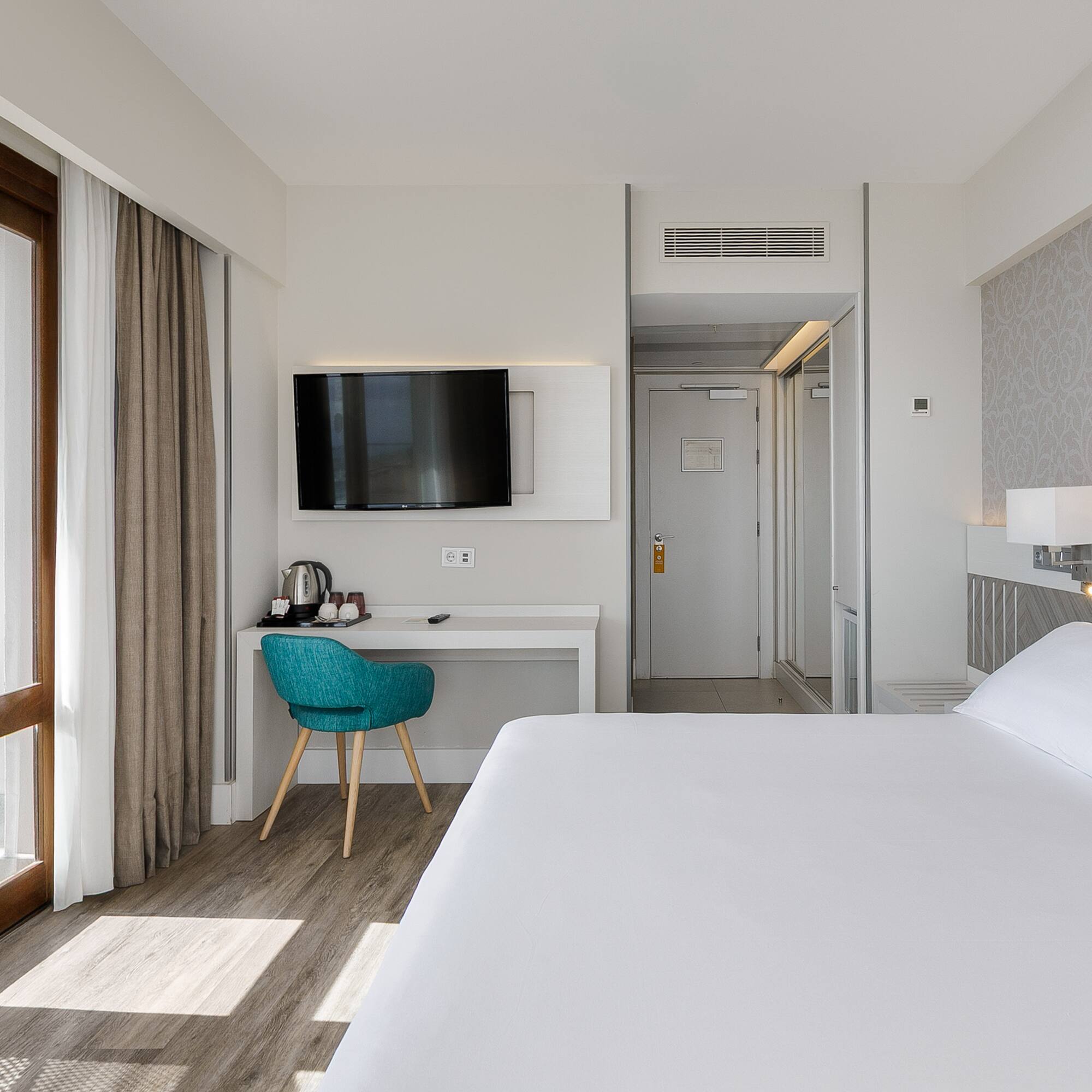 a room with a bed and a desk and a television