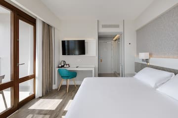 a room with a bed and a desk and a television