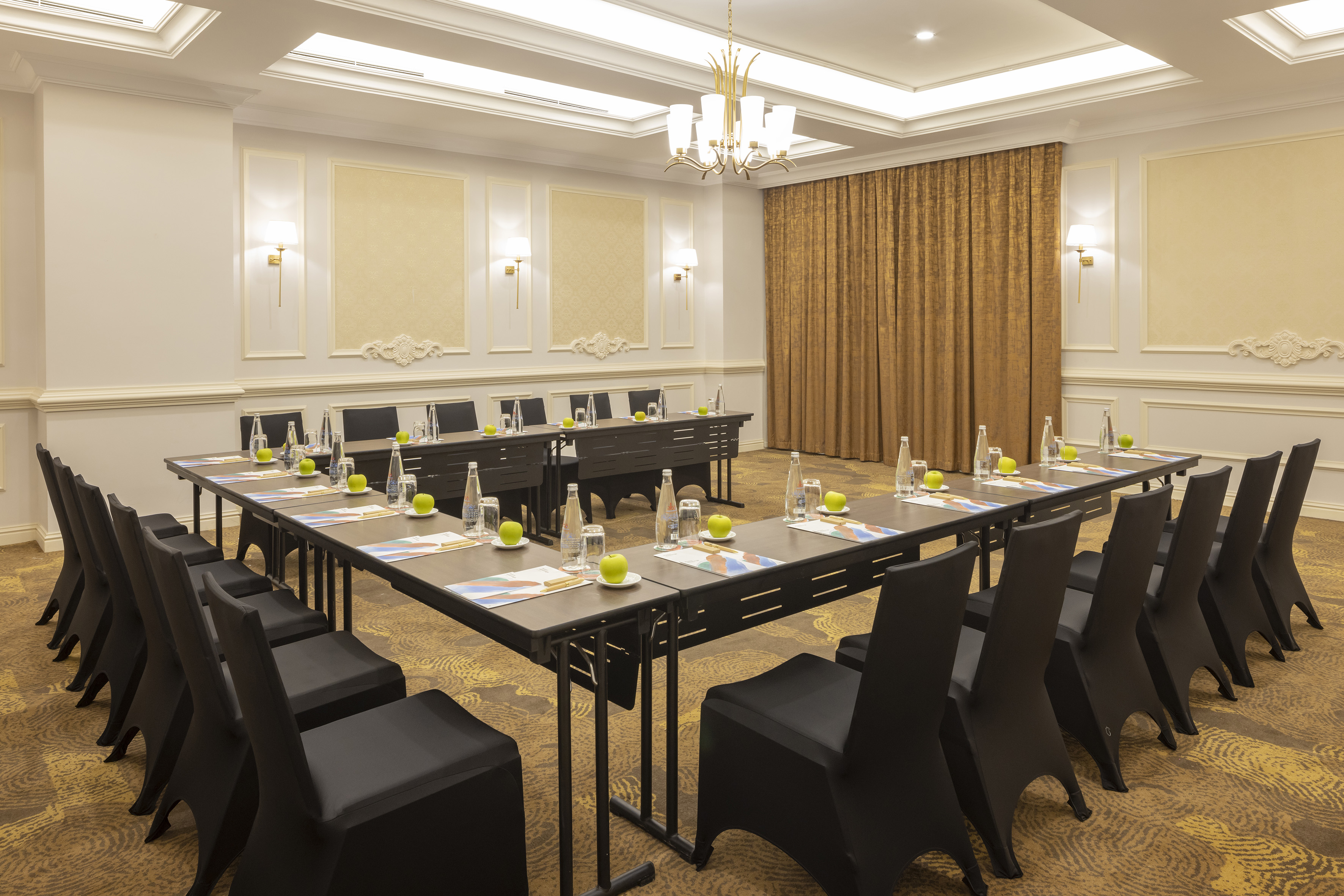 Professional U-shaped conference room setup with black chairs and gold decor.