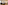 Modern hotel suite with large bed, two armchairs, and herringbone floor.