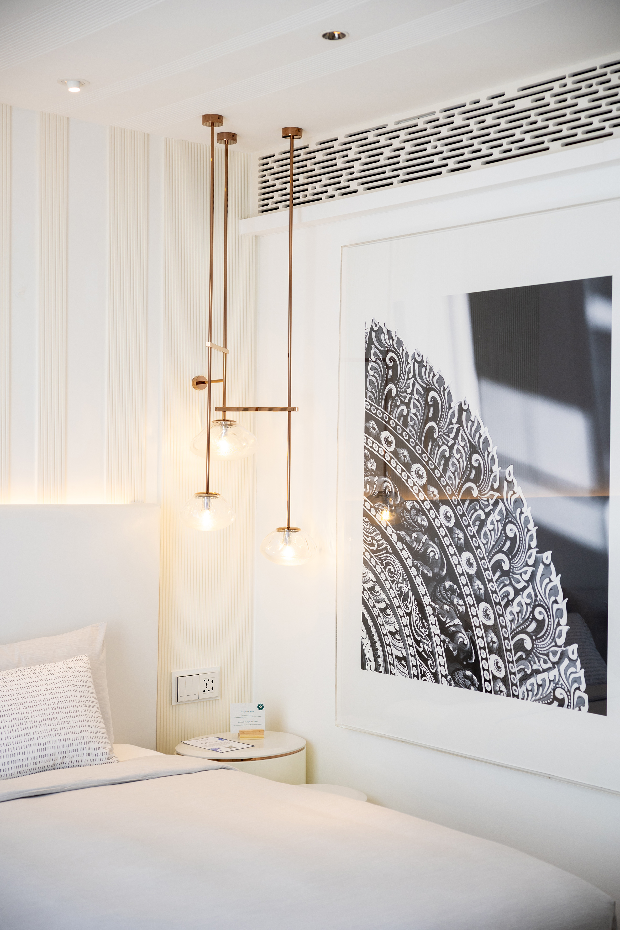Modern white bedroom with gold pendant lights and intricate wall art.