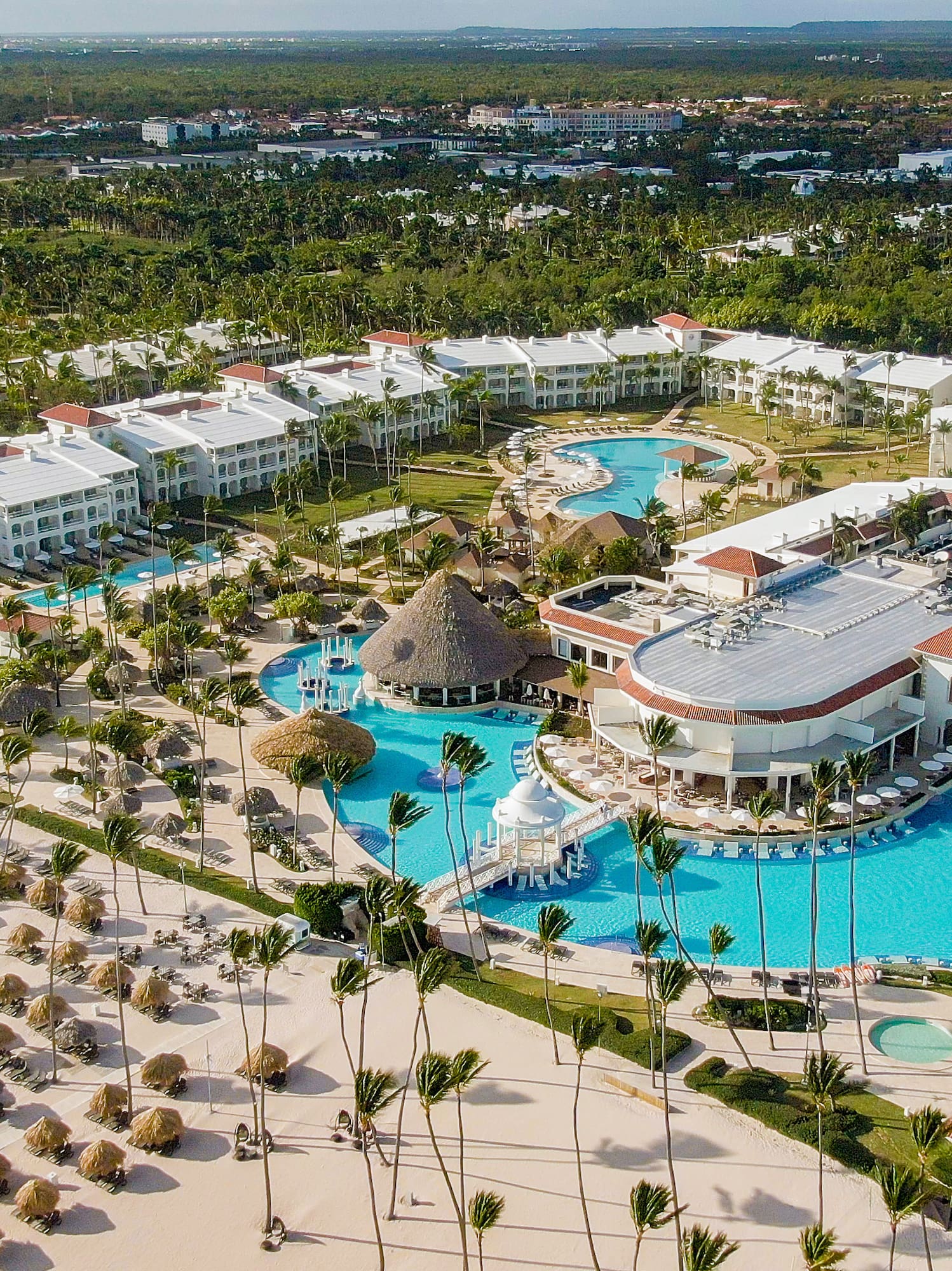 Luxury beach resort with pools, sandy beach, and tropical palm trees.