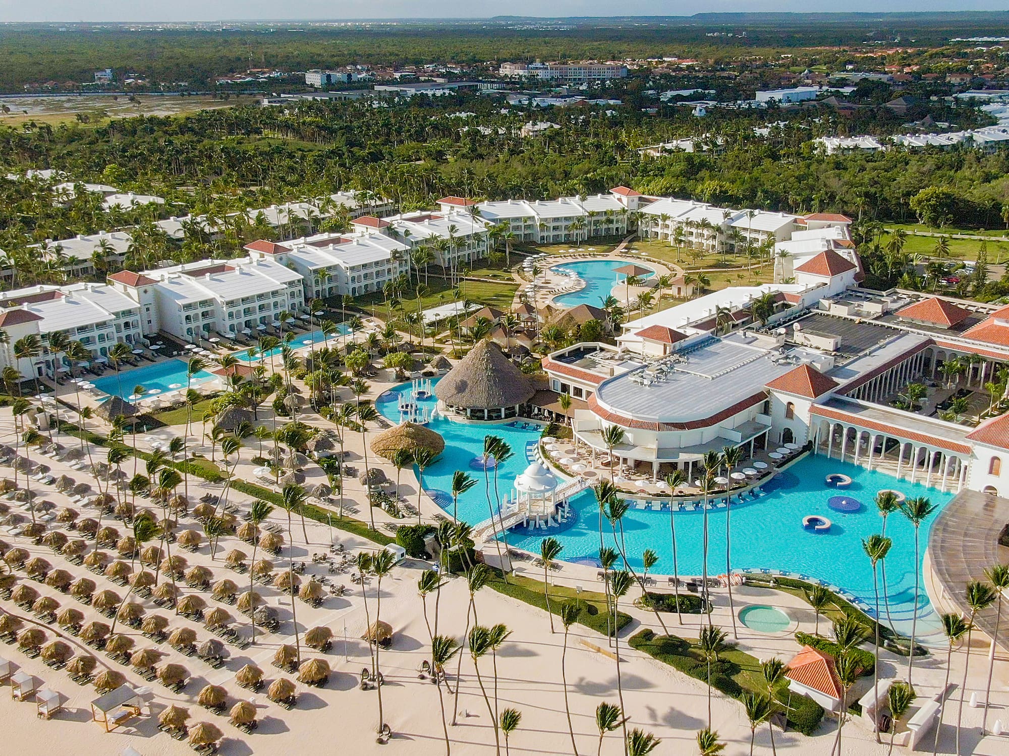 Luxury beach resort with pools, sandy beach, and tropical palm trees.