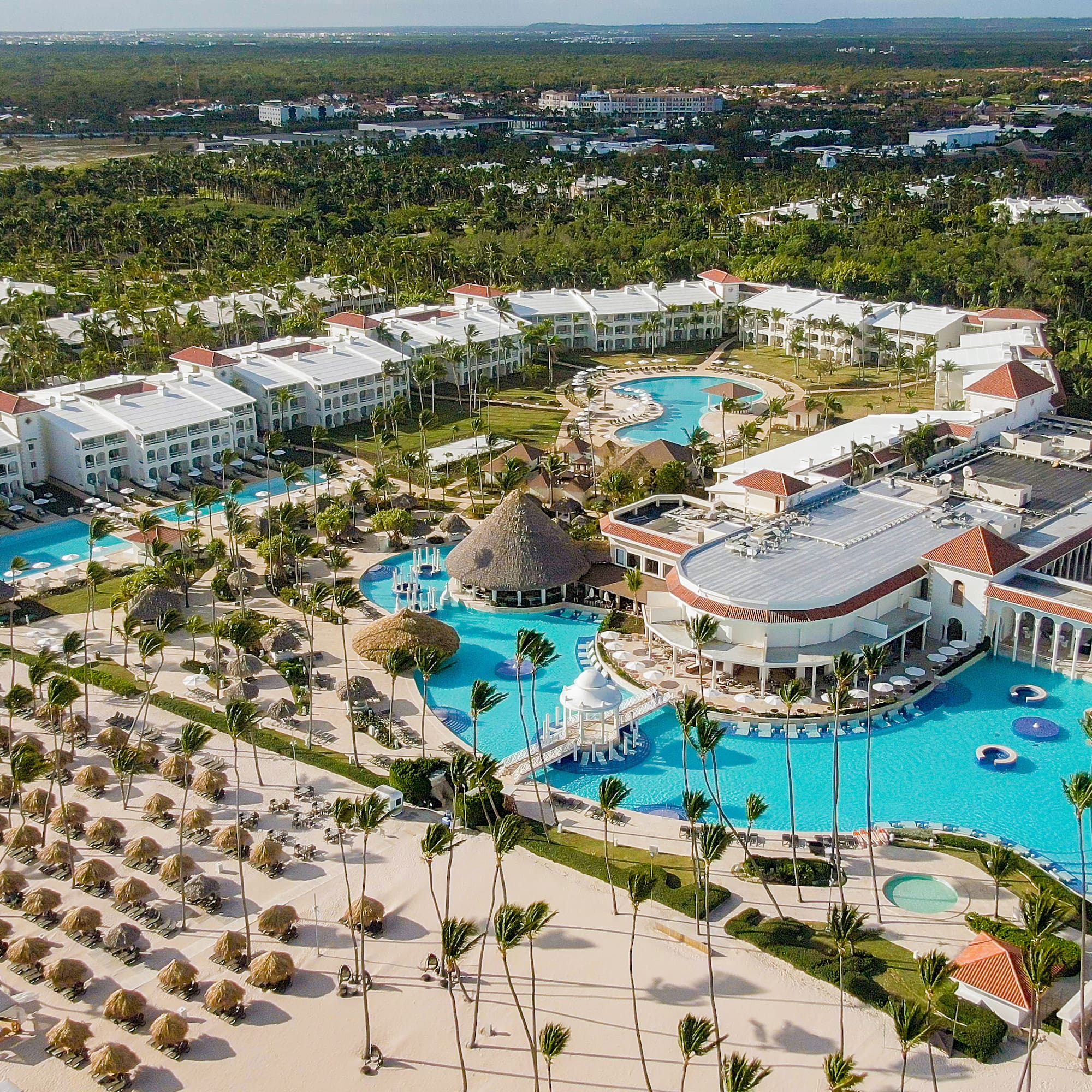 Luxury beach resort with pools, sandy beach, and tropical palm trees.
