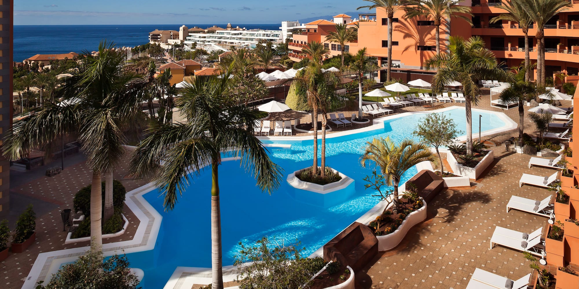 a pool with palm trees and a beach in the background