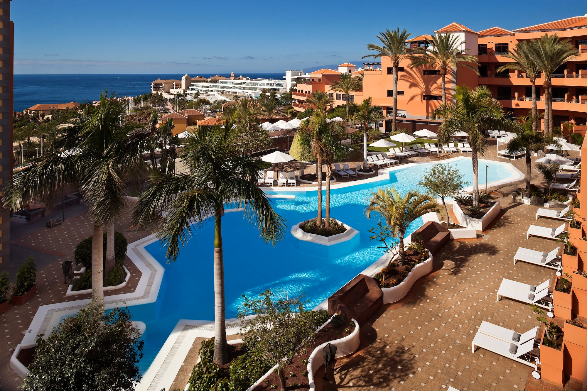 a pool with palm trees and a beach in the background