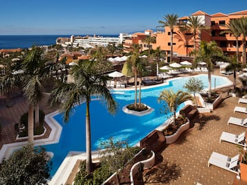 a pool with palm trees and a beach in the background