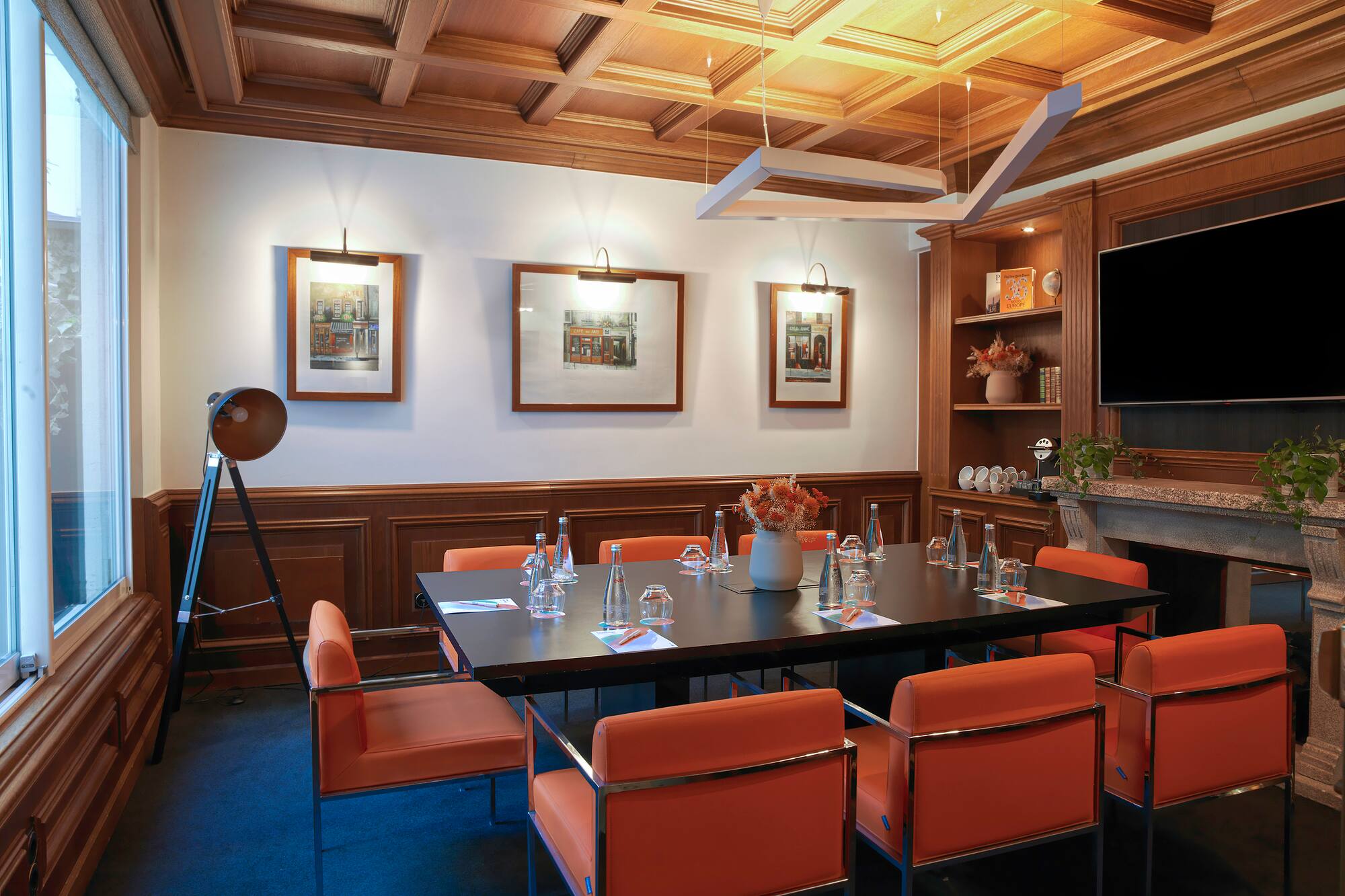 Elegant meeting room with orange chairs, dark table, and wooden details.