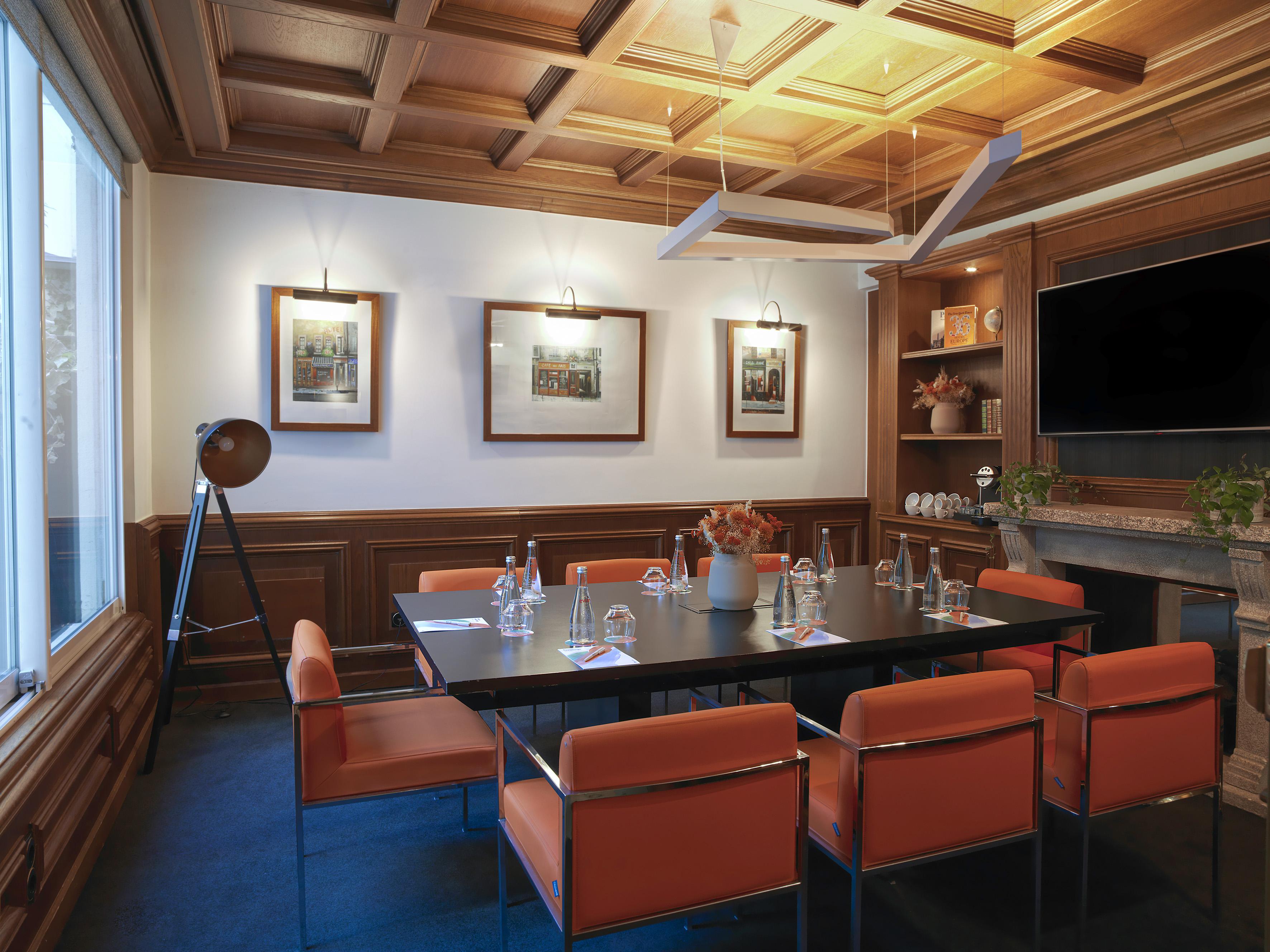 Elegant meeting room with orange chairs, dark table, and wooden details.