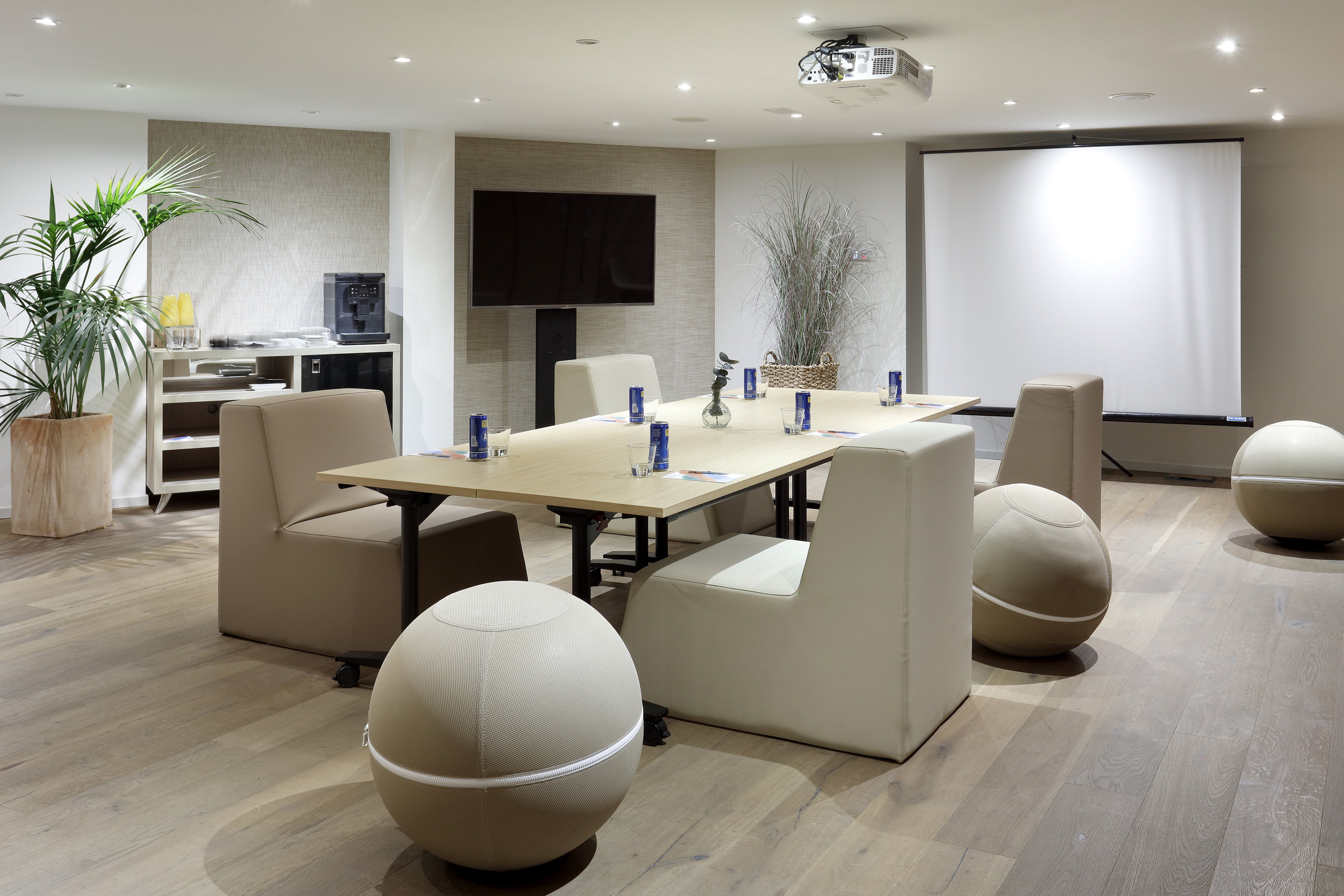 Modern conference room with projector screen, TV, and diverse seating.