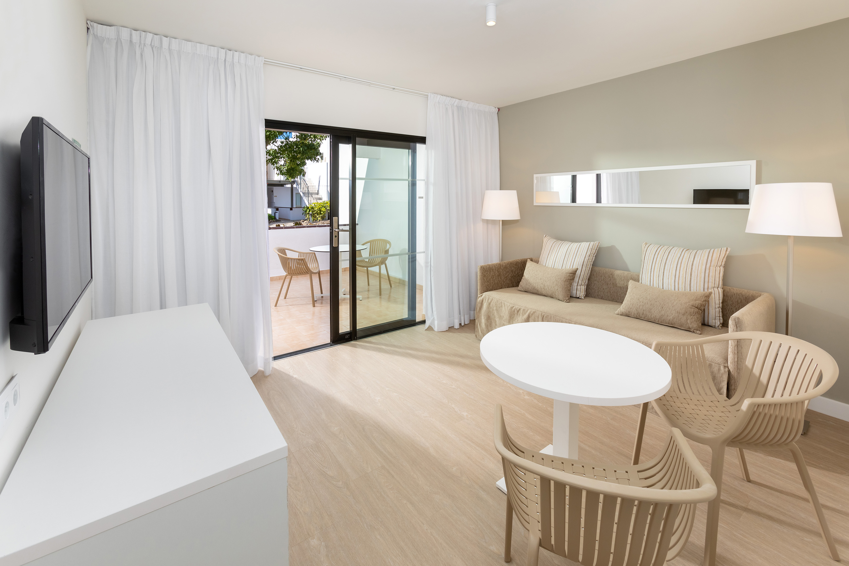 Contemporary living room interior with sofa, TV, balcony, light wood floor.