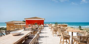 a restaurant with tables and chairs on a rooftop overlooking the ocean