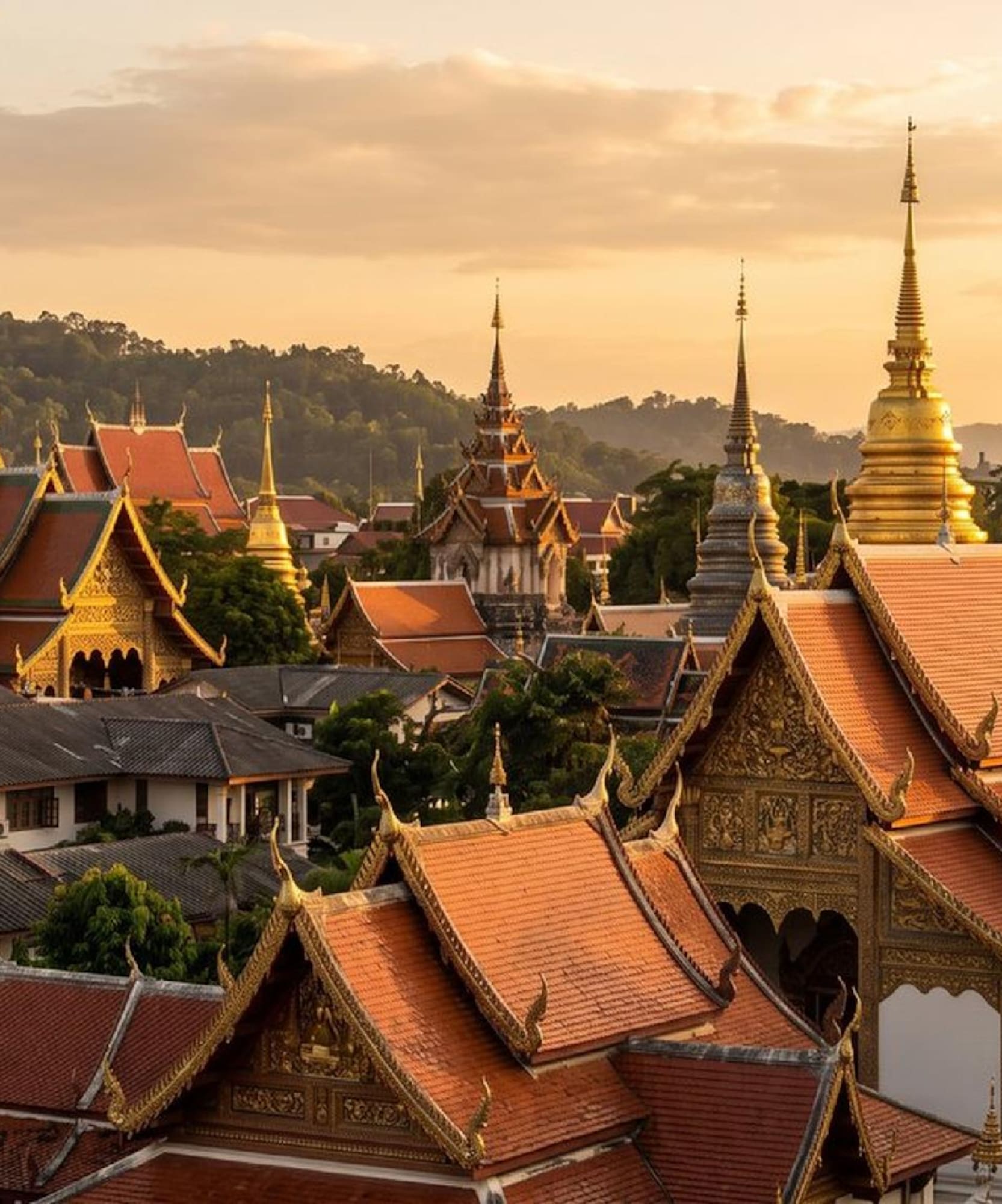 Golden spires and red-tiled roofs of Thai temples at sunset.