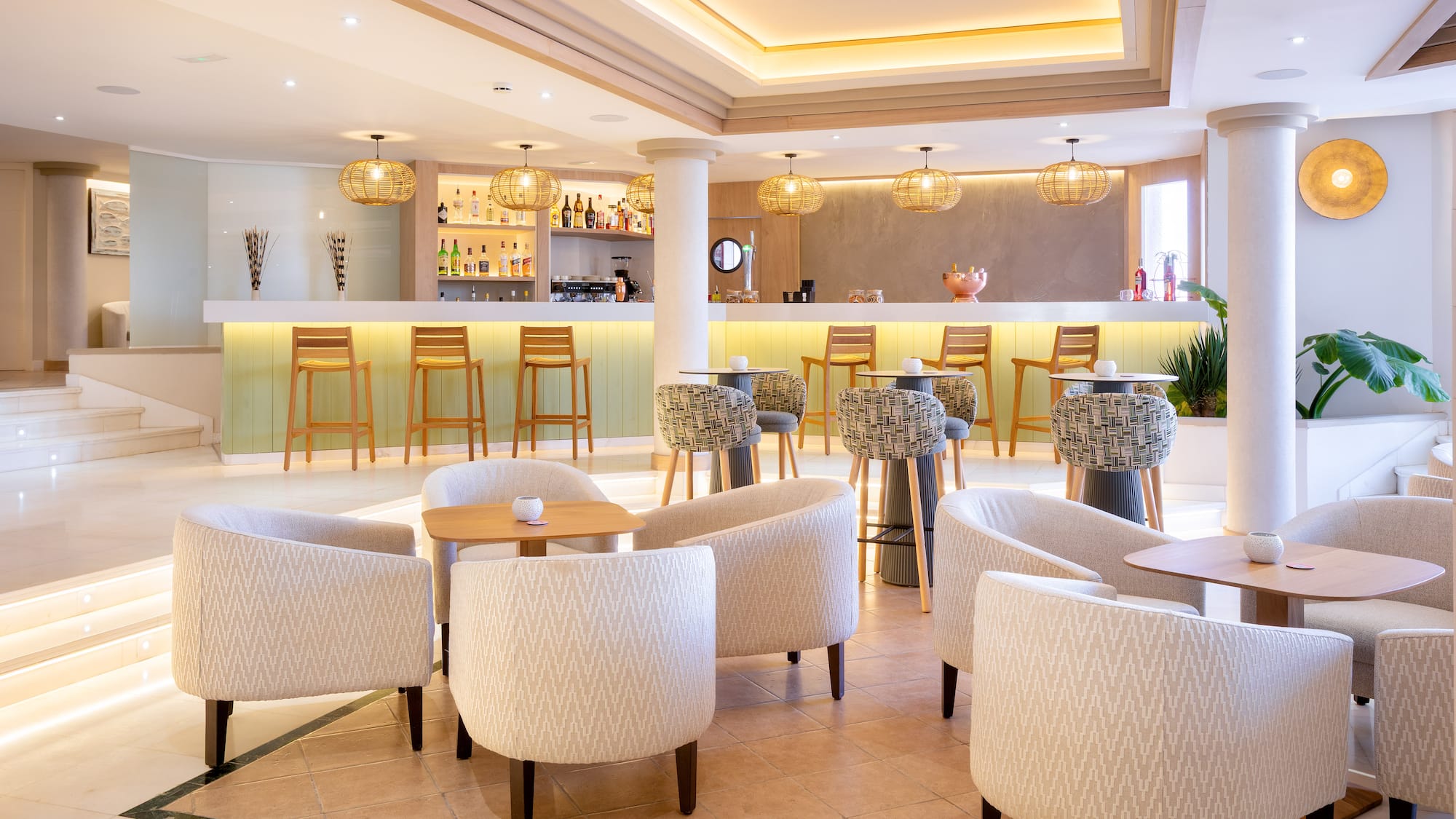 Modern resort bar with light wood, bar stools, and lounge seating.