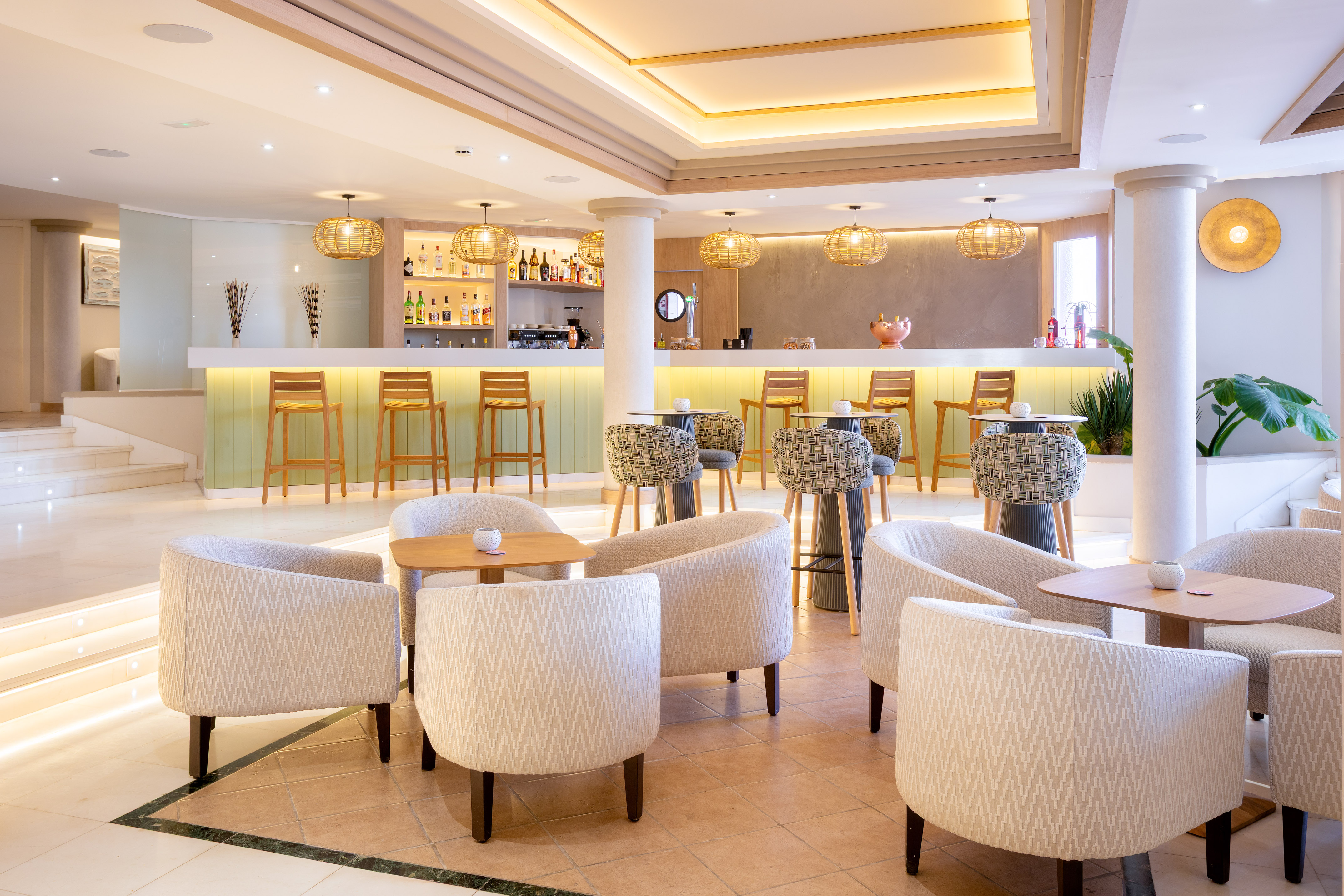 Modern resort bar with light wood, bar stools, and lounge seating.